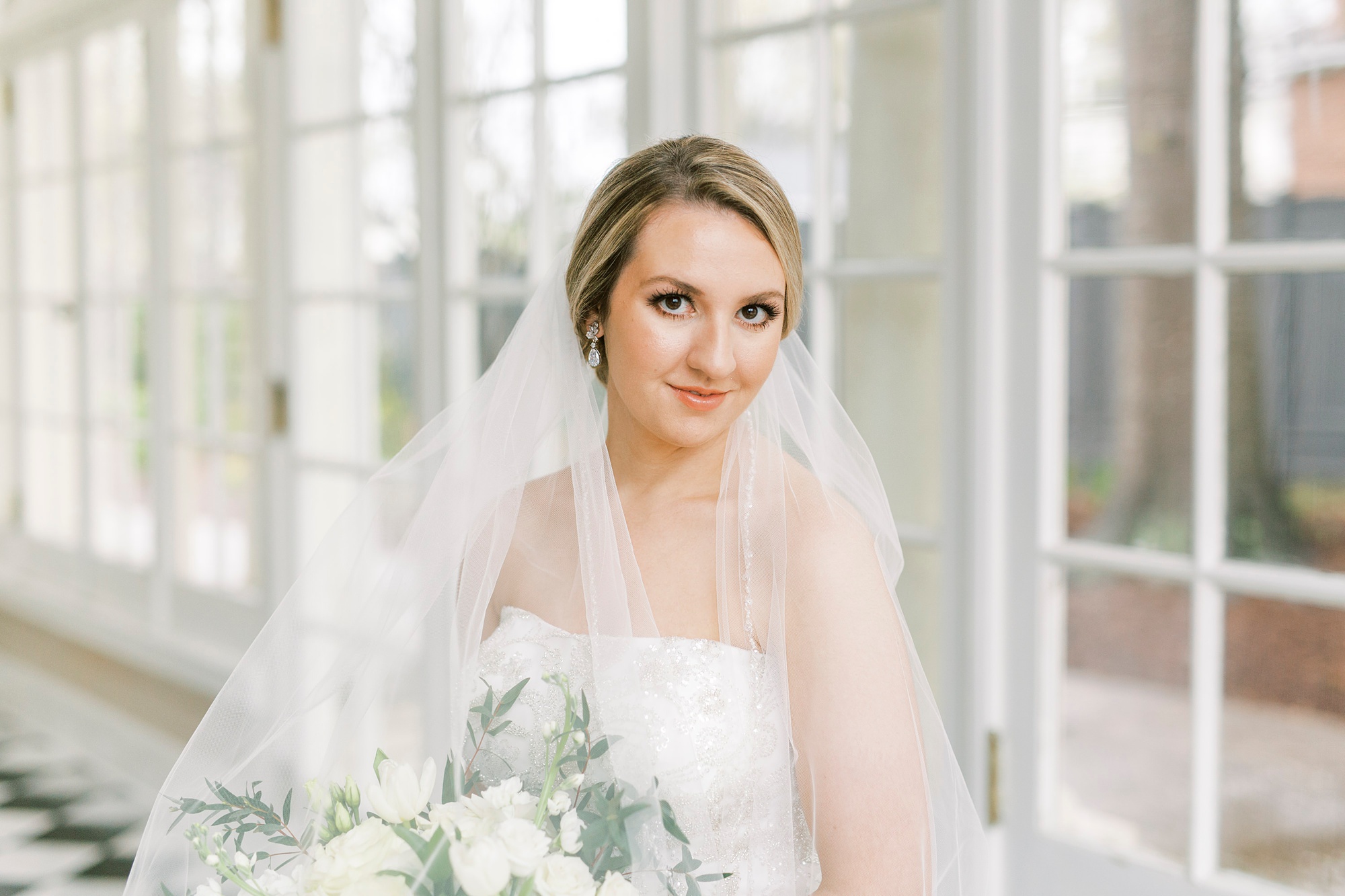 bride looks at camera with ivory flowers