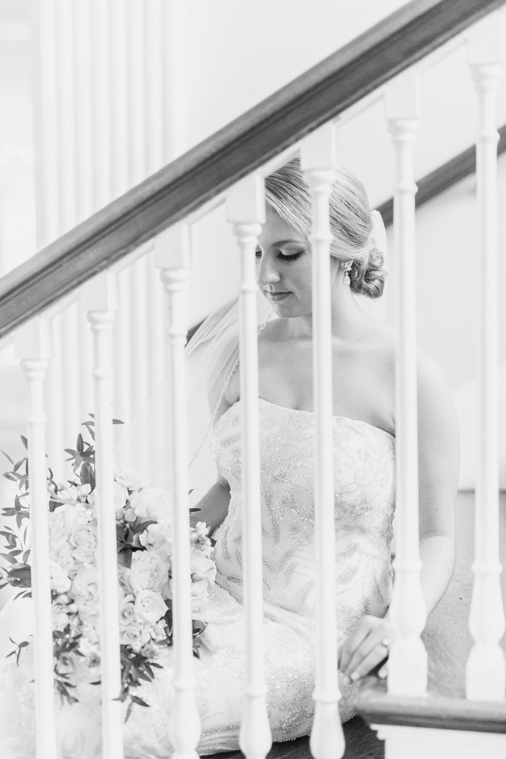 bride sits on staircase in Separk Mansion with cathedral veil around shoulders