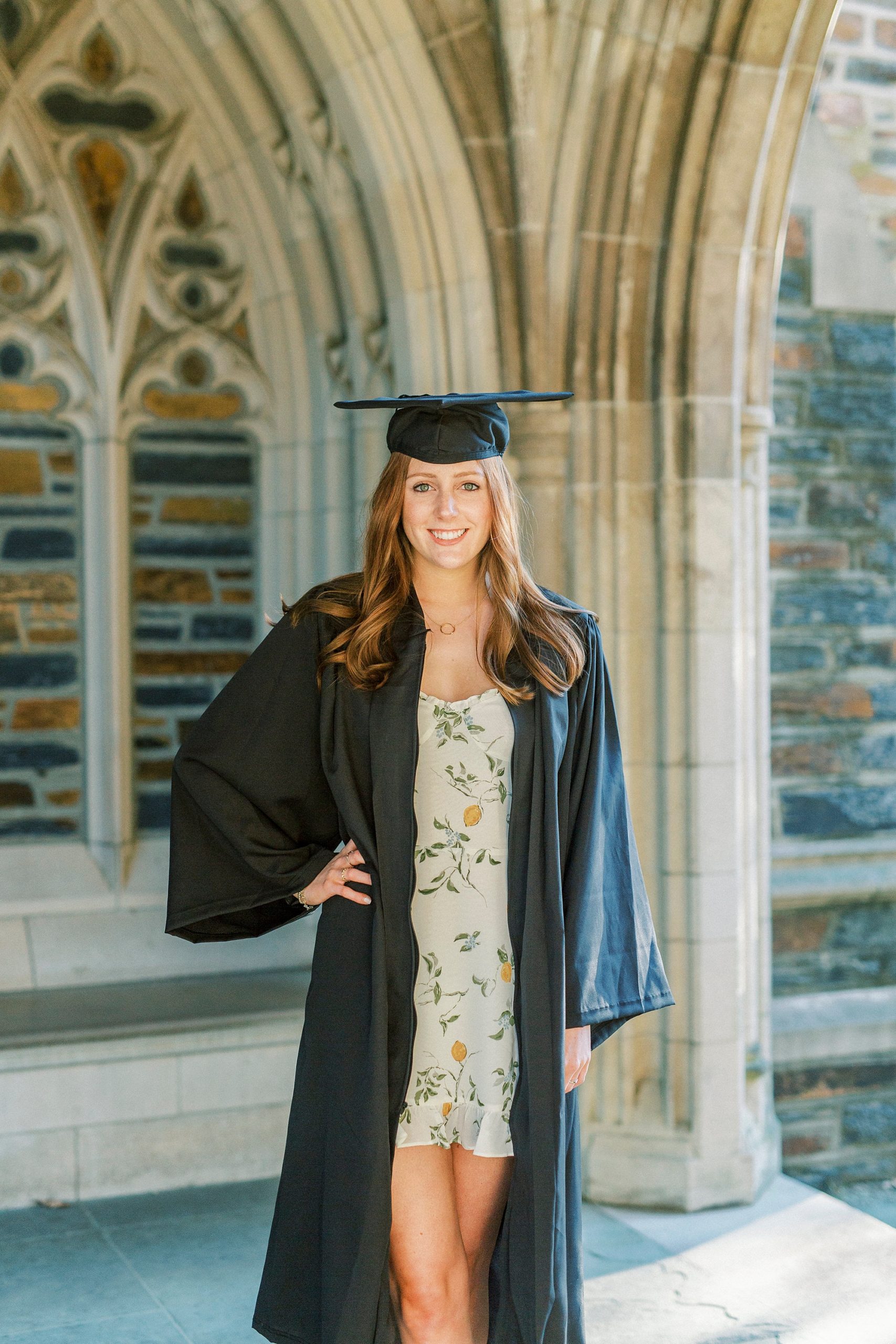 college senior poses with cap and gown during Duke University graduation portraits