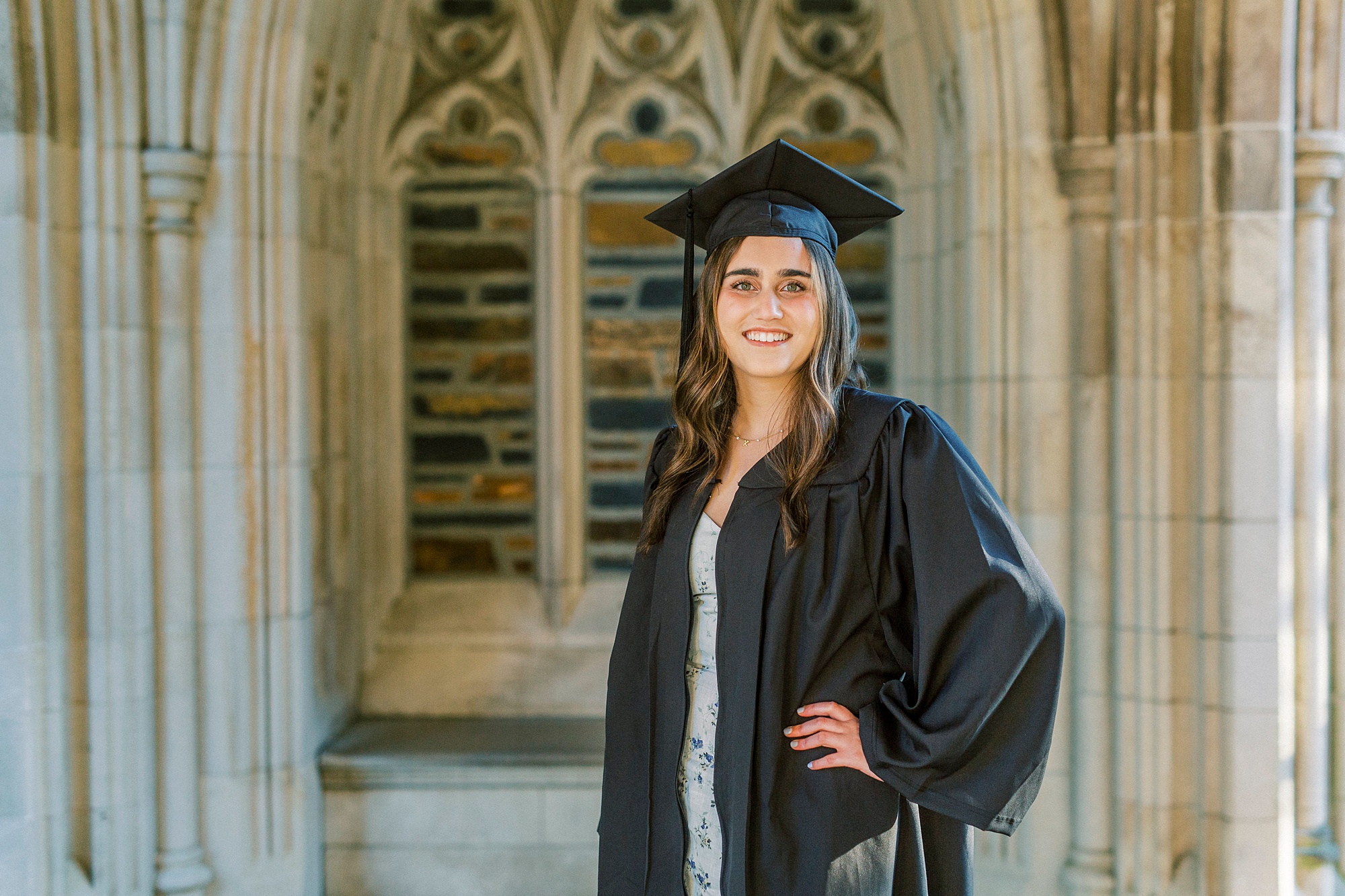 senior poses in black cap and gown by Duke Chapel