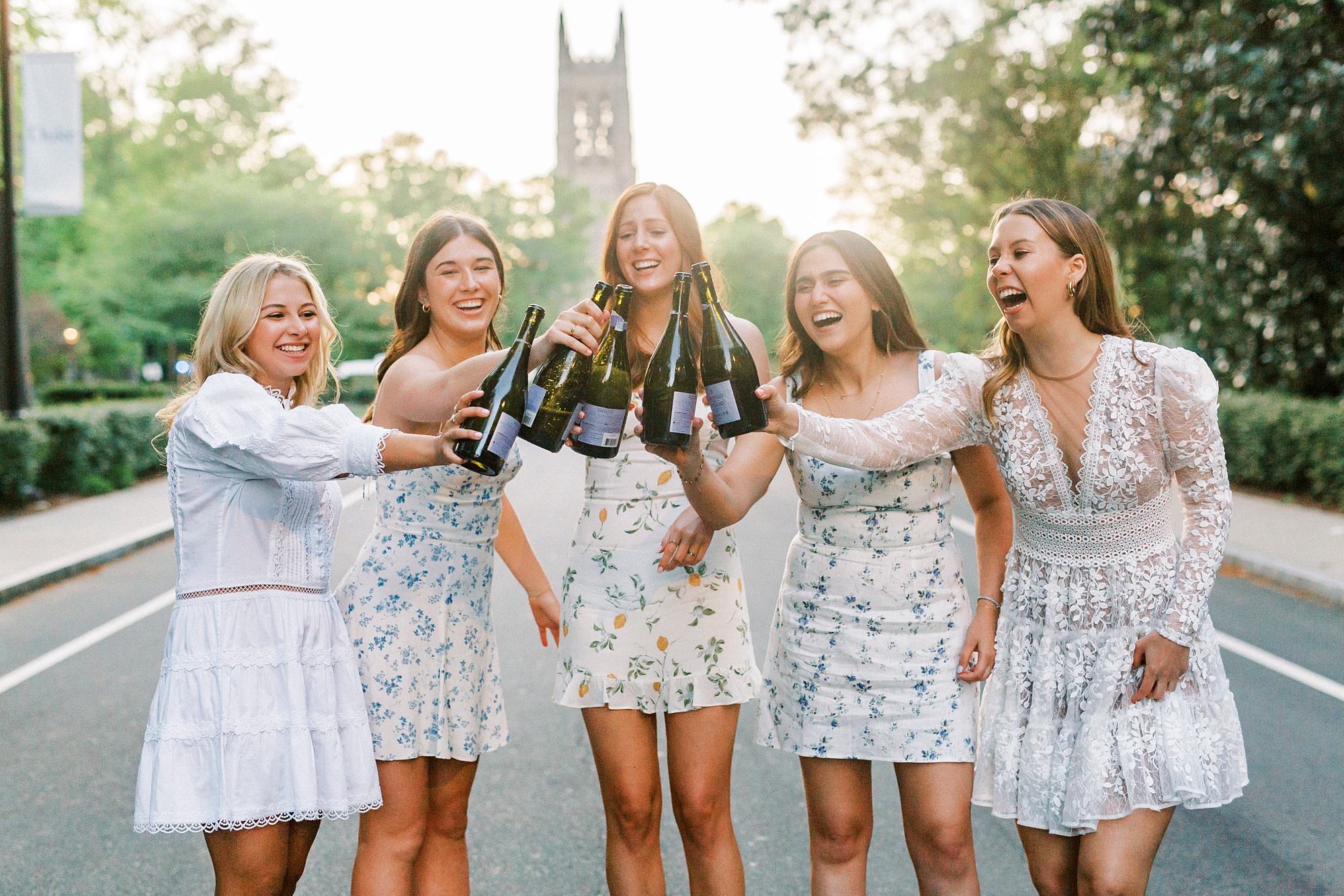 college grads toast with bottles of champagne