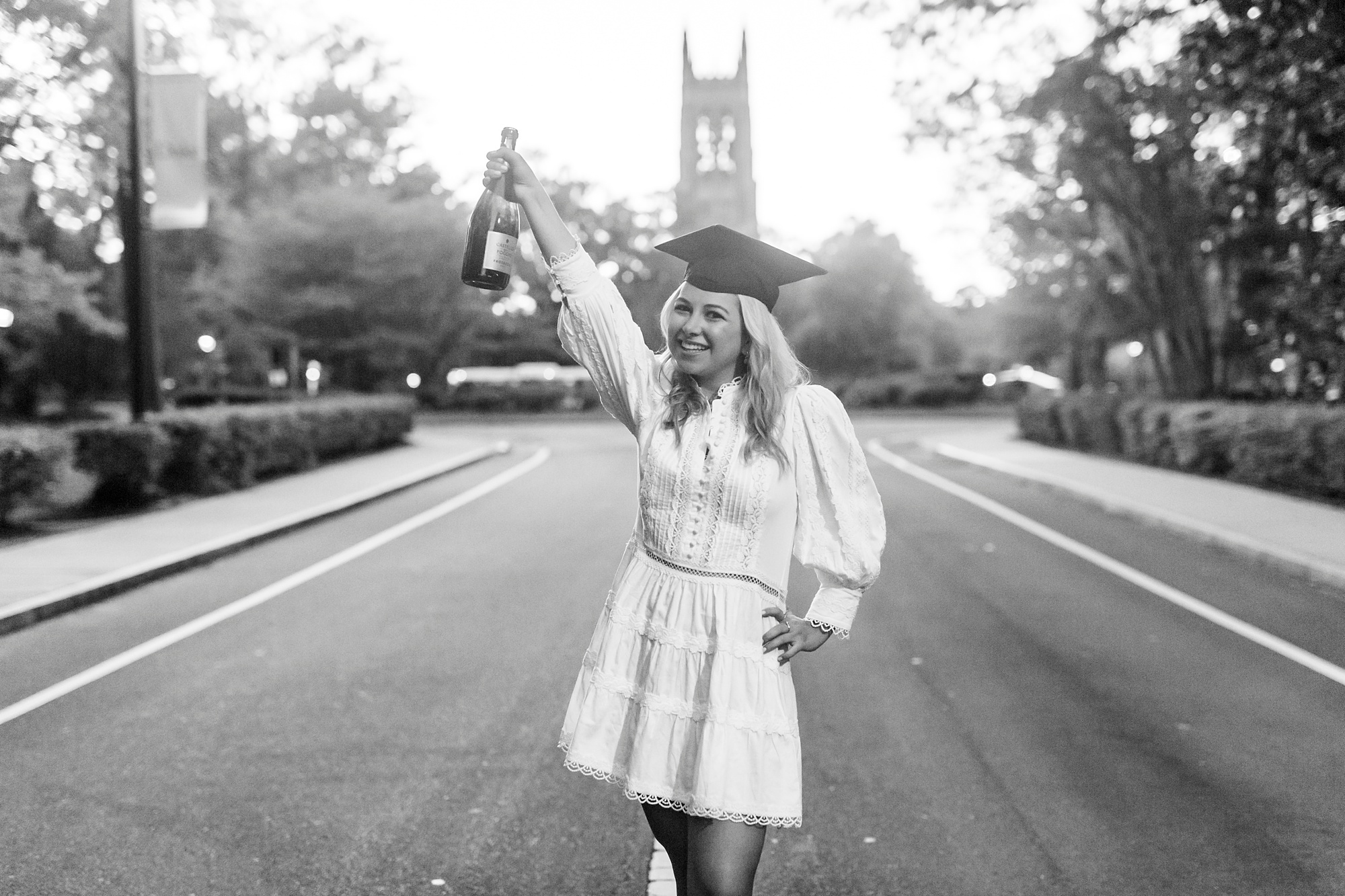 senior holds champagne bottle up during Duke University graduation portraits