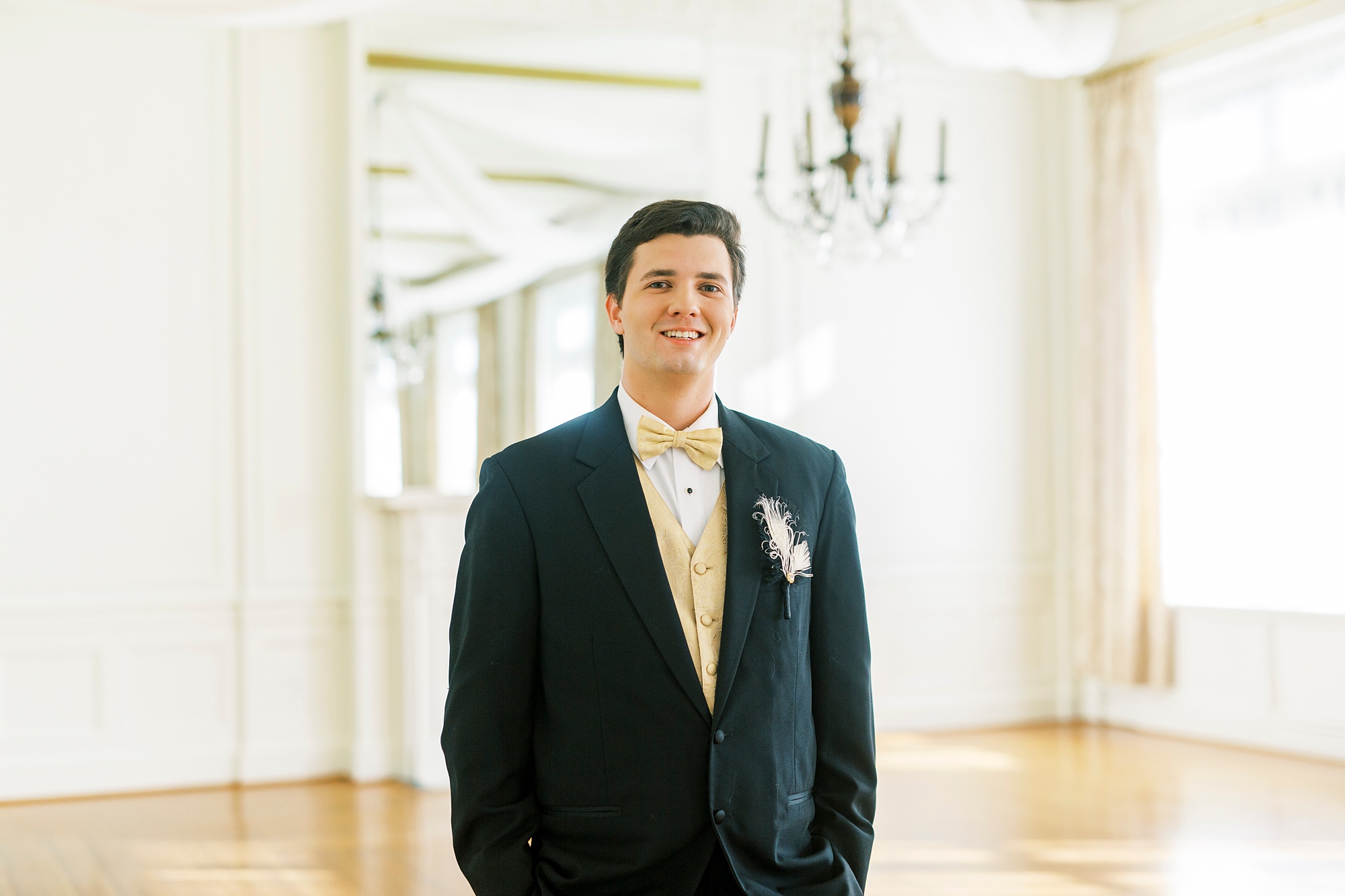 young man in suit with gold vest and tie poses in ballroom at Hotel Concord