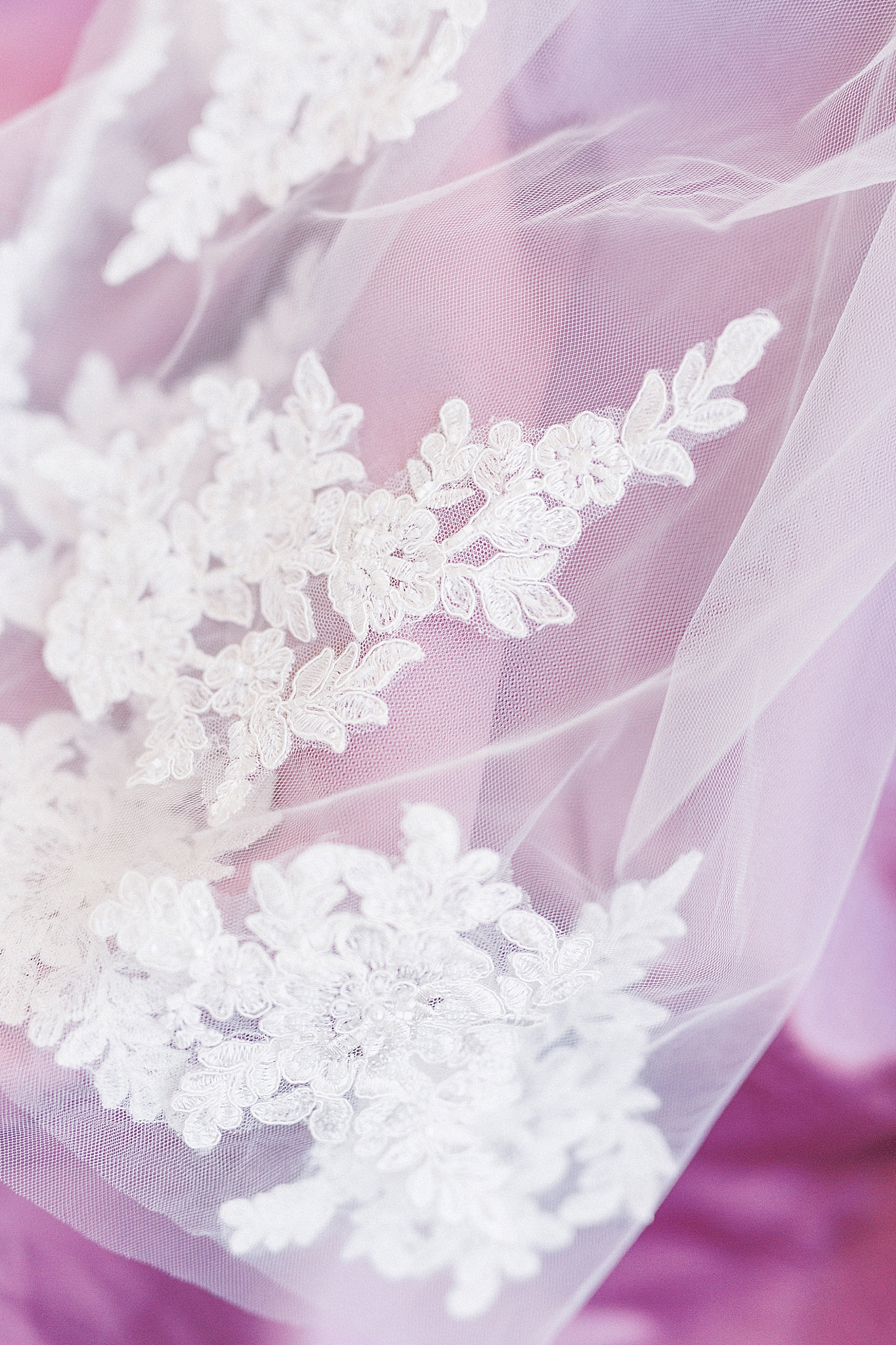 lace from bride's veil lays on pink fabric