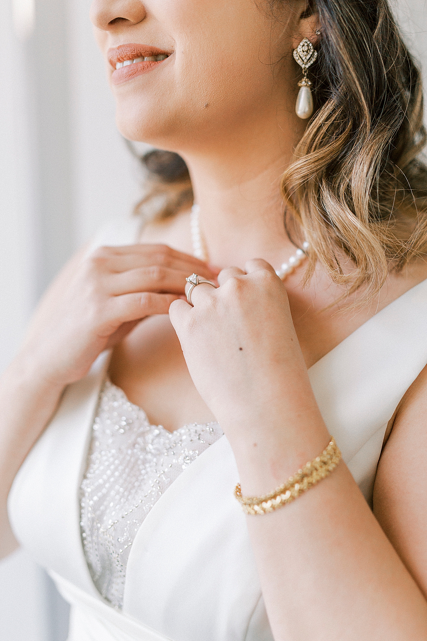 bride adjusts family jewelry before wedding day