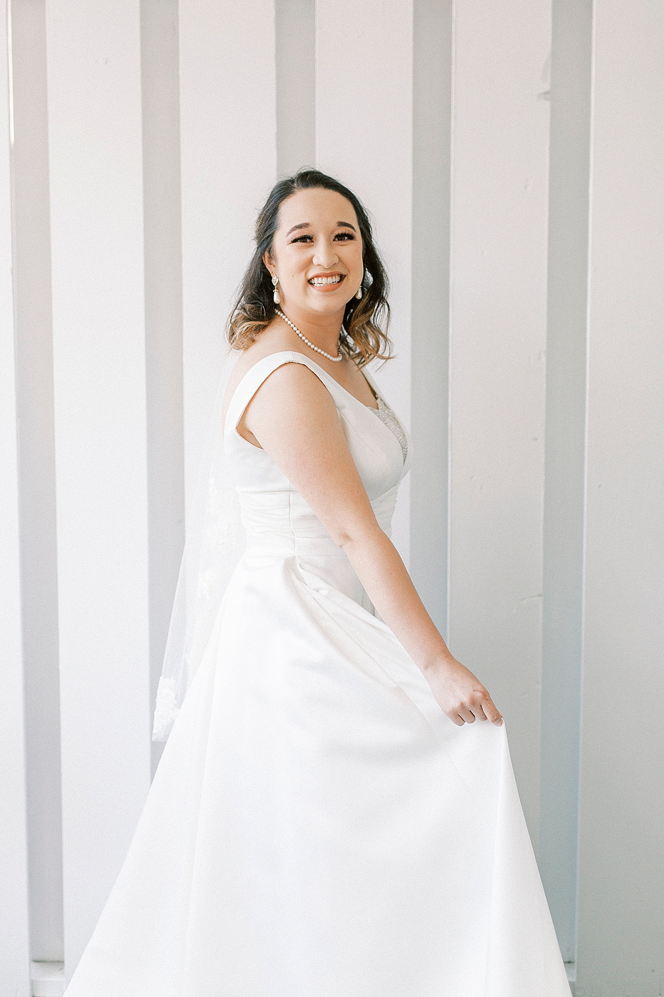 bride twirls wedding dress by striped wall