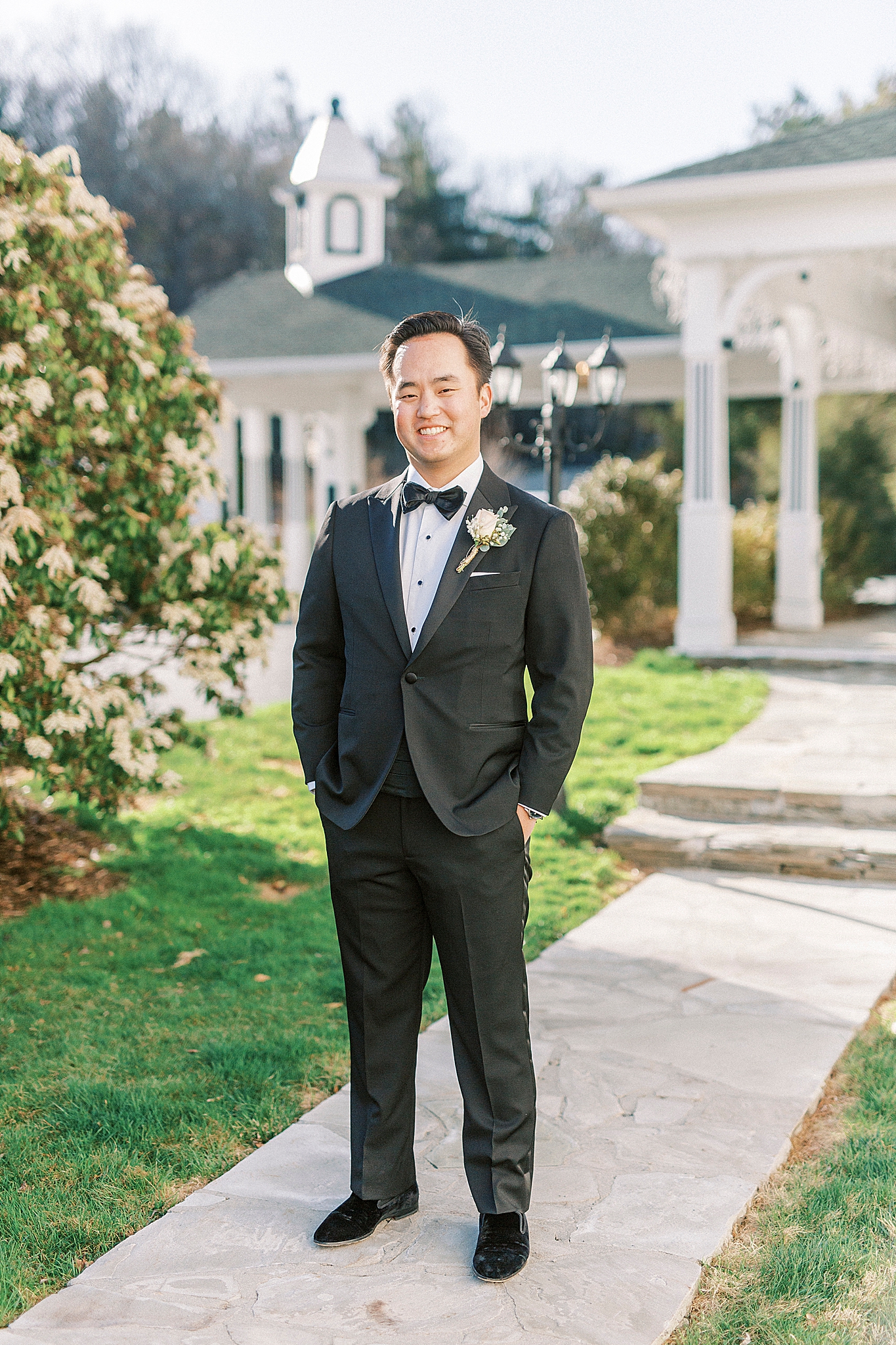 groom poses on walkway in classic black tux
