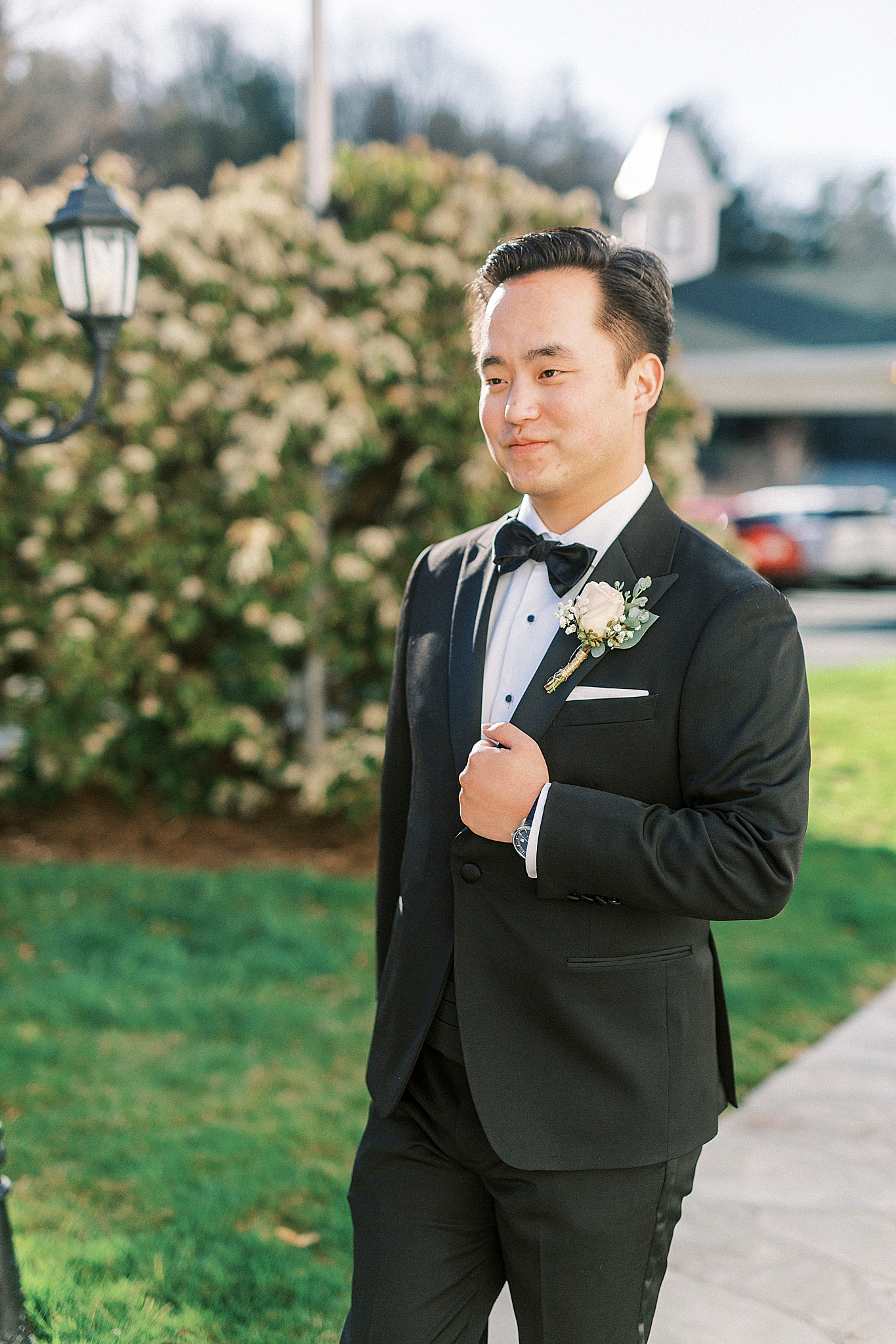groom in classic tux holds edge of suit jacket