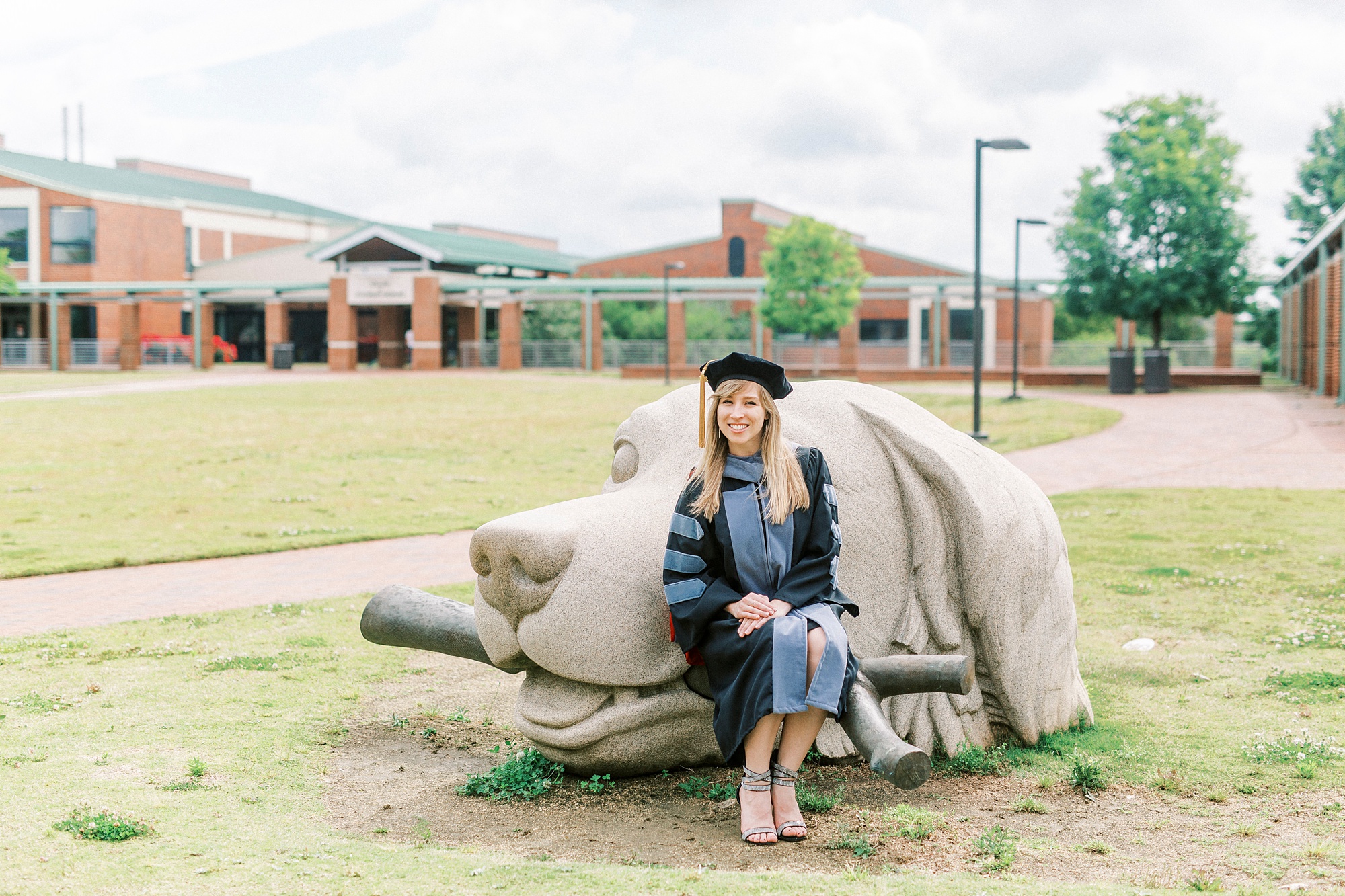 grad poses by dog statue at NC State Vet School