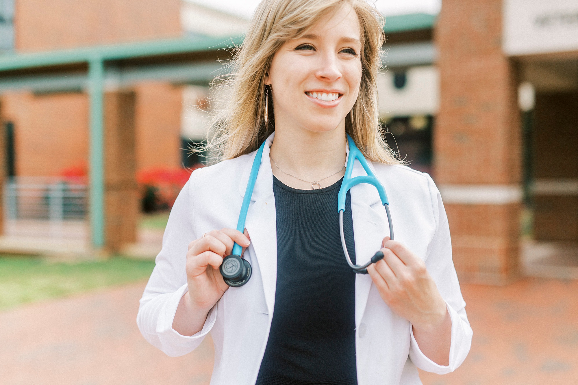 graduate poses with white coat and stethoscope