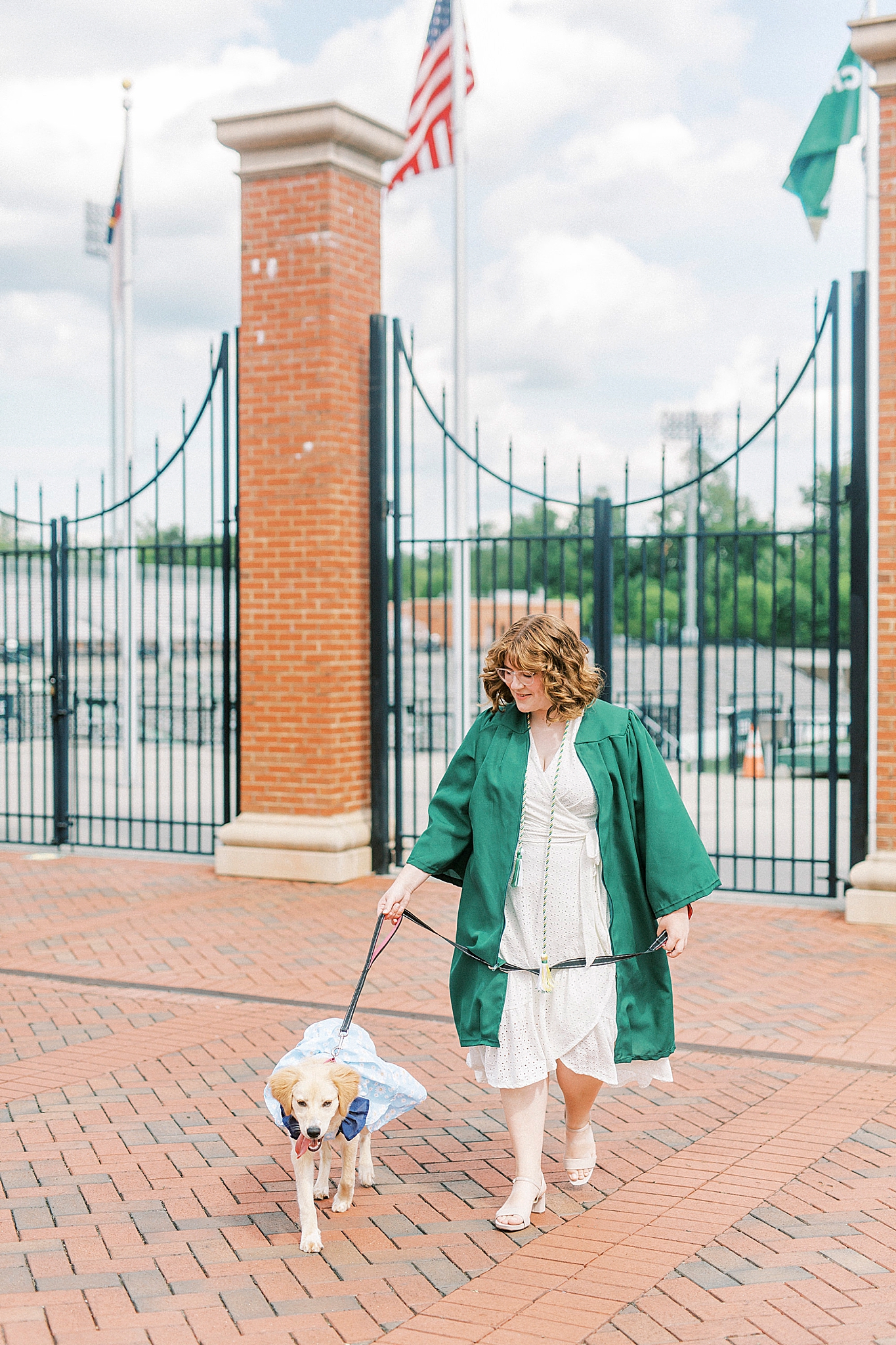 graduate walks with dog in blue dress for senior photos