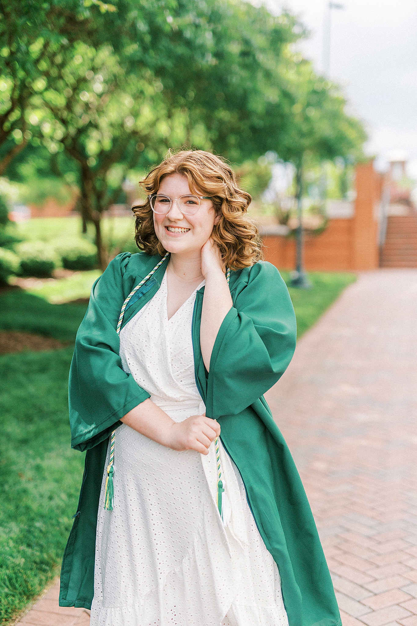 graduate poses with hand behind her neck