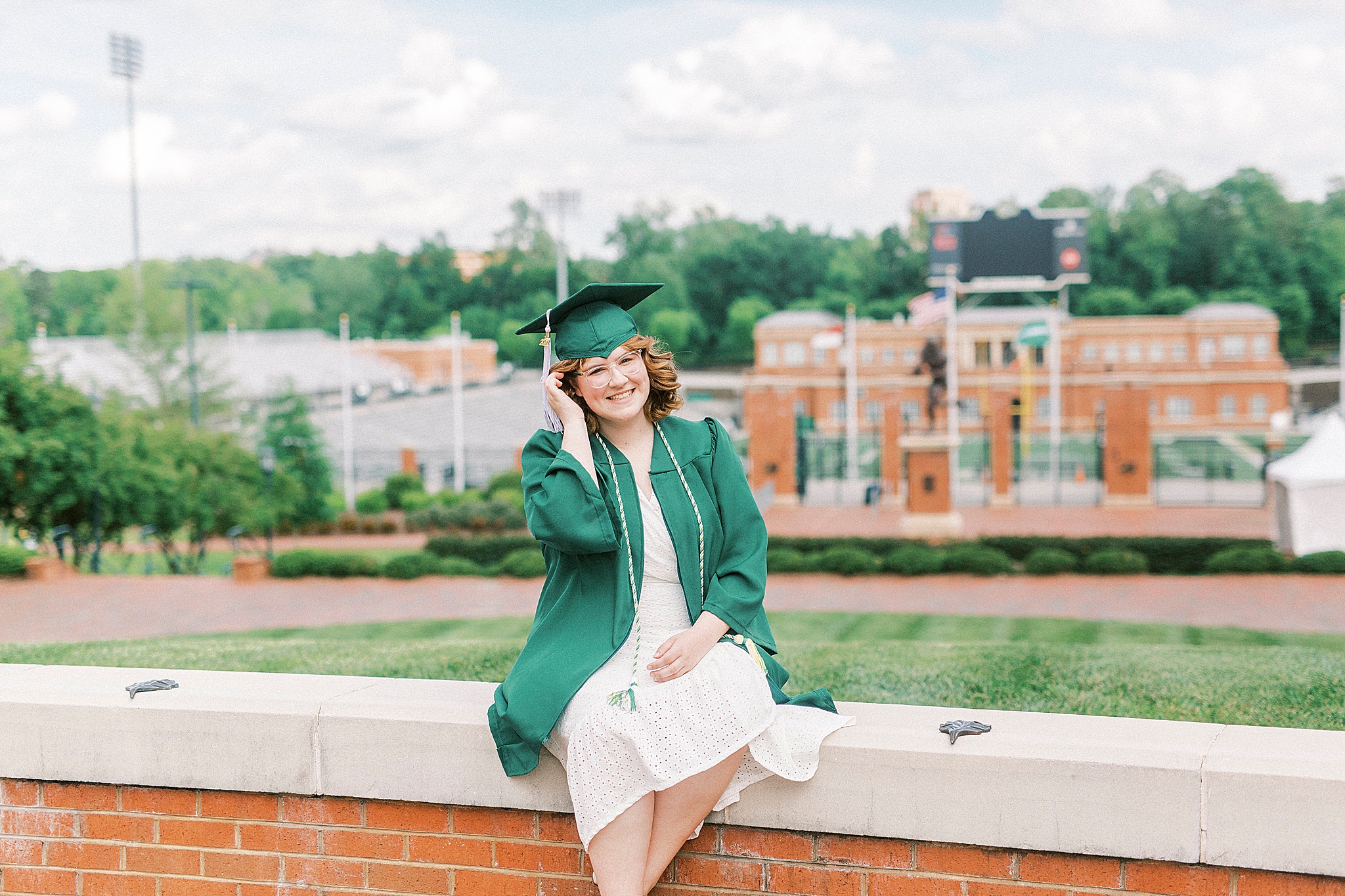 senior sits in front of football field at UNCC