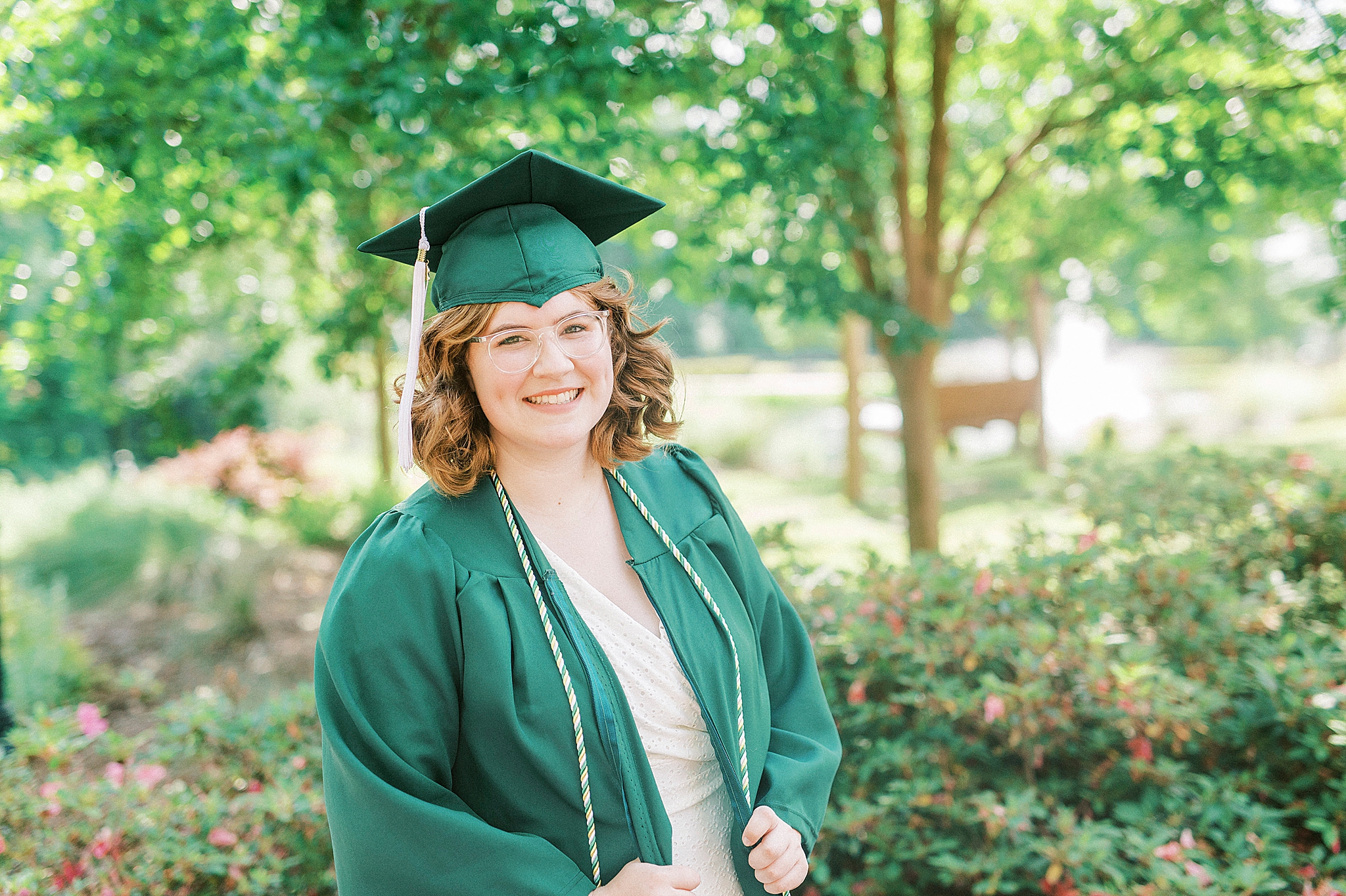 college graduate poses in green robe and cap
