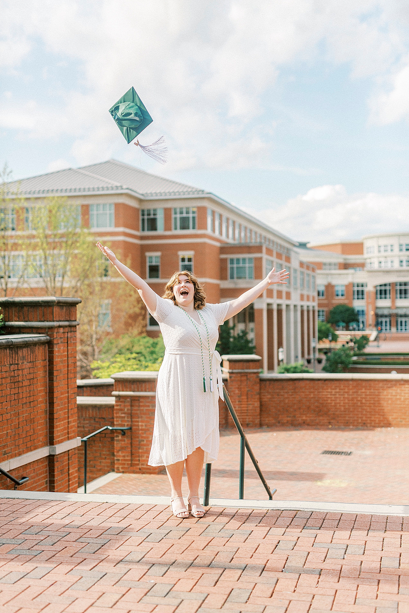 graduate throws cap in the air during UNCC senior pictures