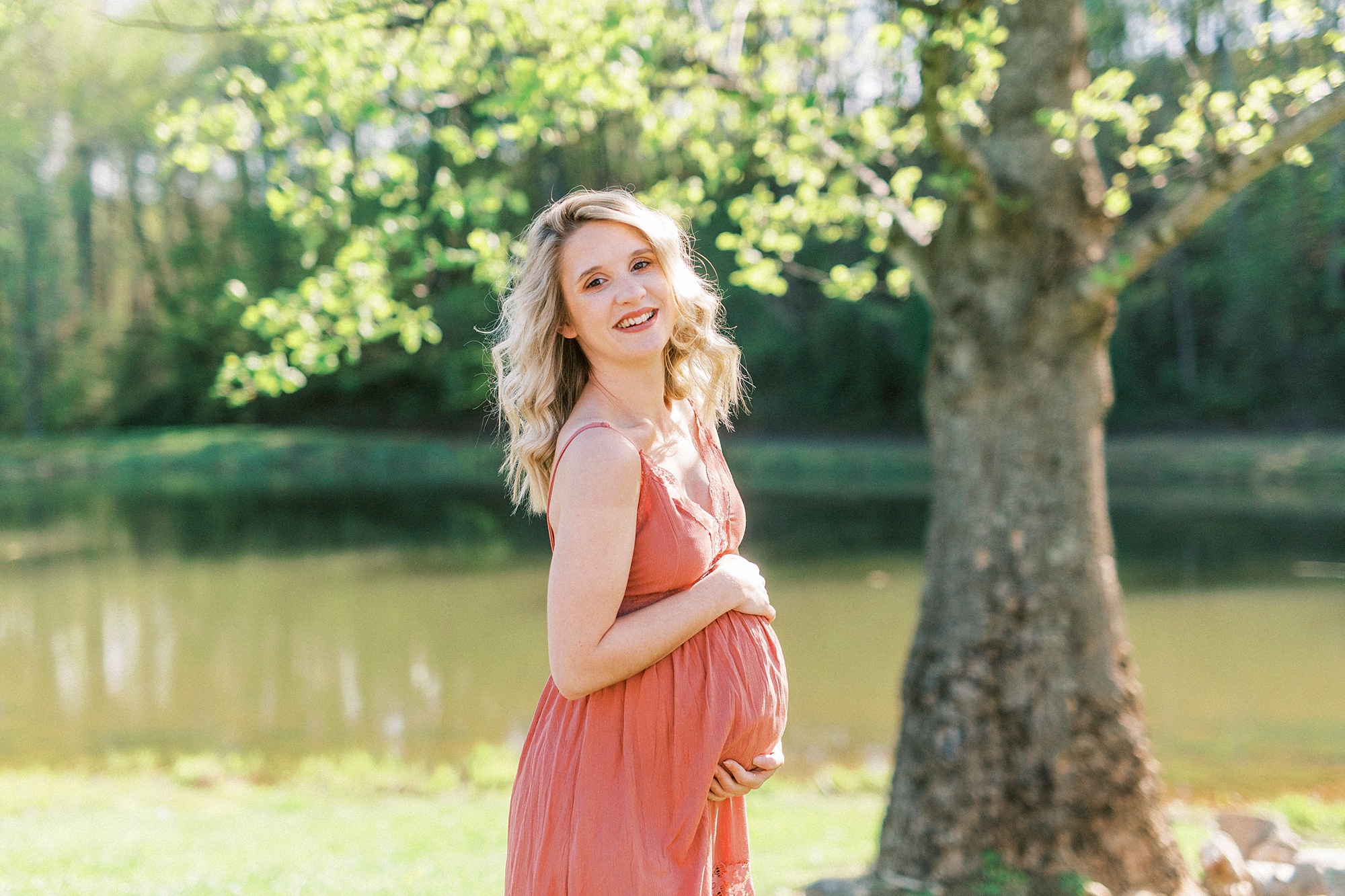 woman laughs holding belly in pink sundress