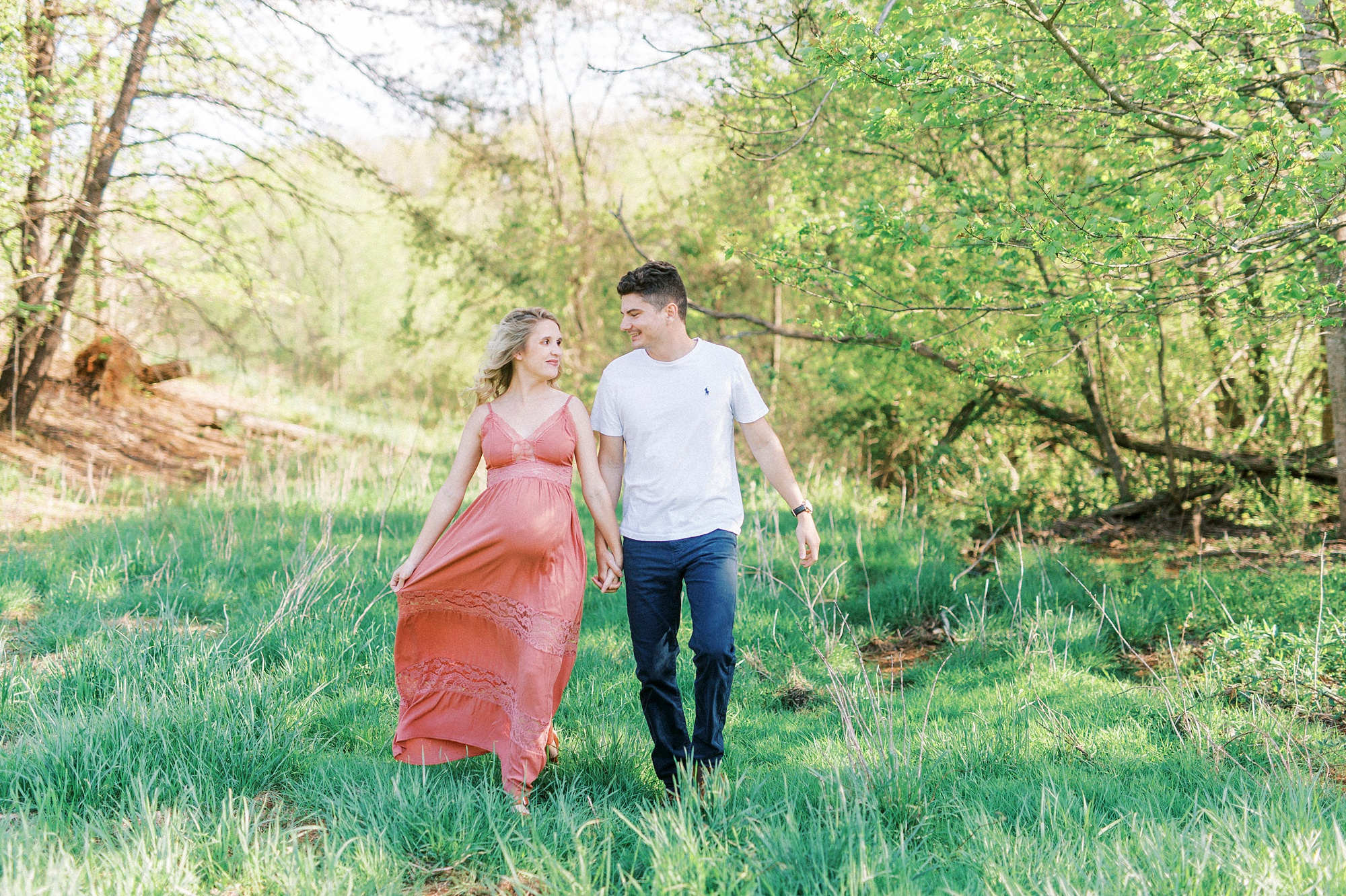 couple walks through field during Winston-Salem maternity photos