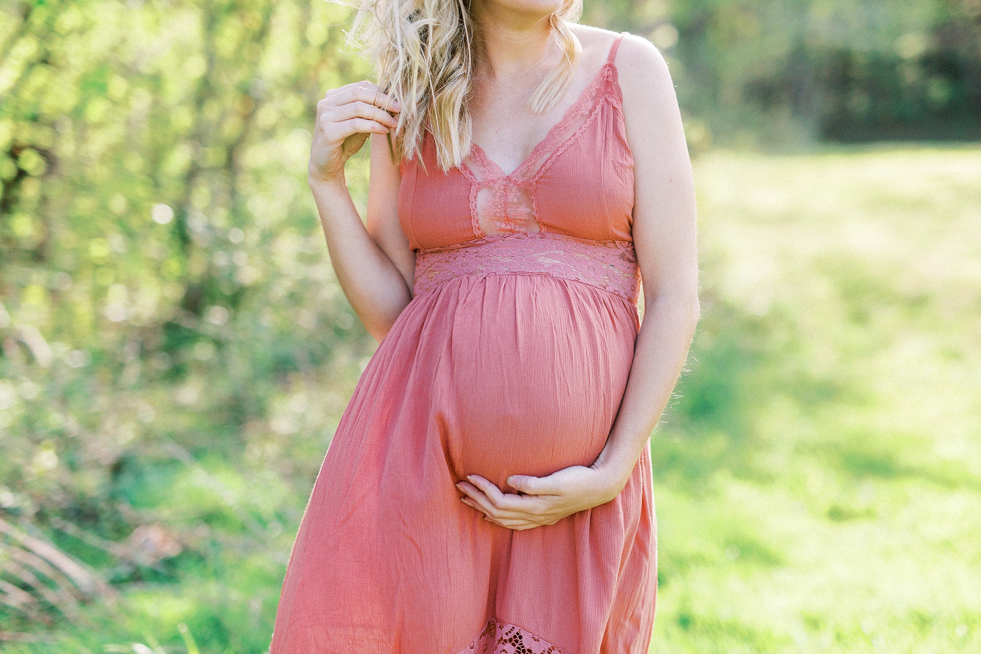 expecting mother in pink gown holds belly