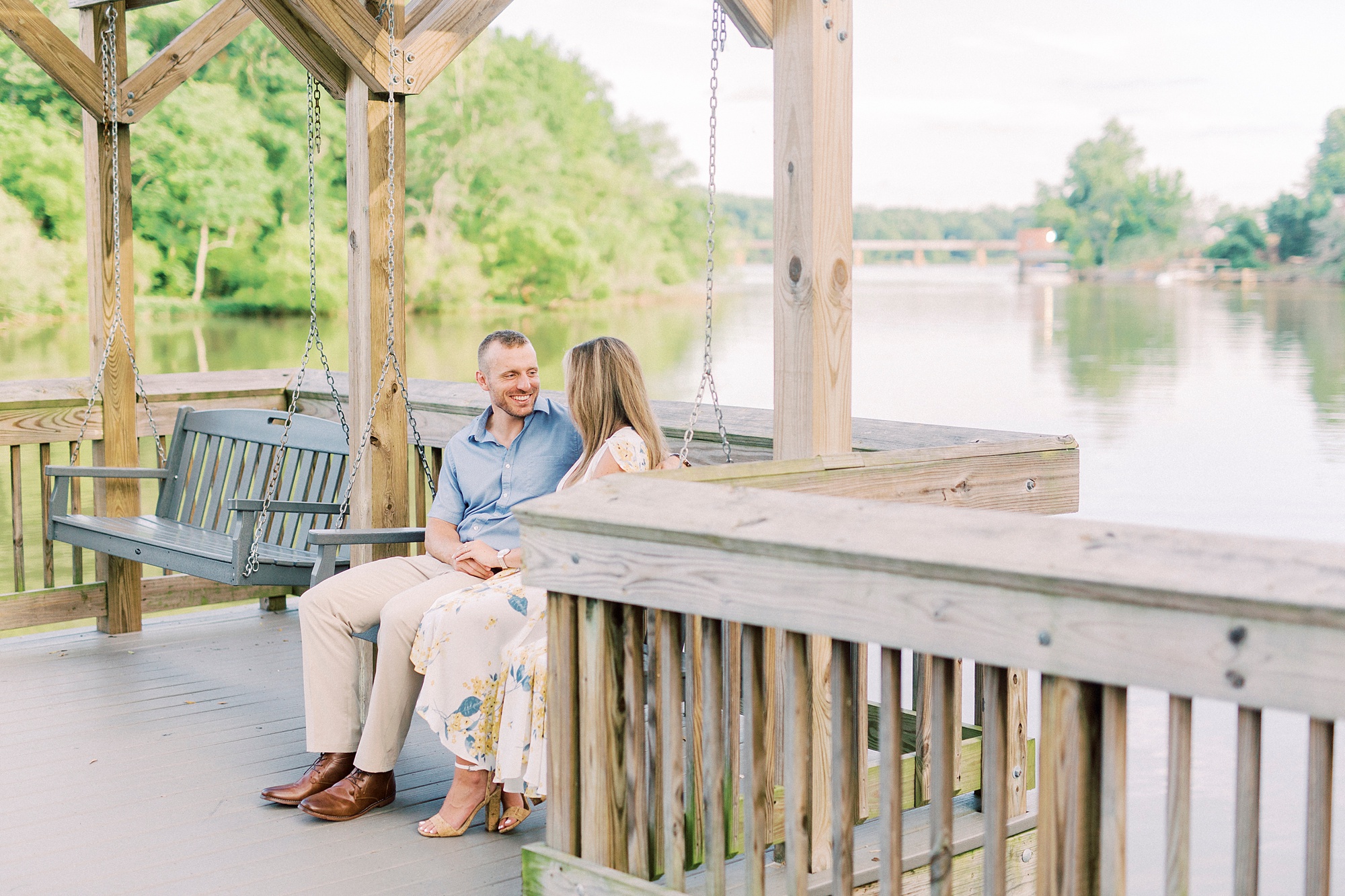 bride and groom sit on wooden pier during Downtown Belmont engagement session