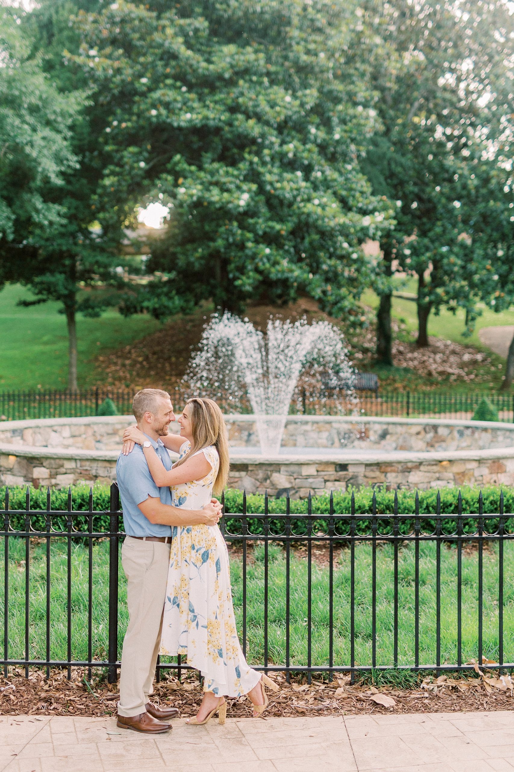 engaged couple poses by fountain in Downtown Belmont park