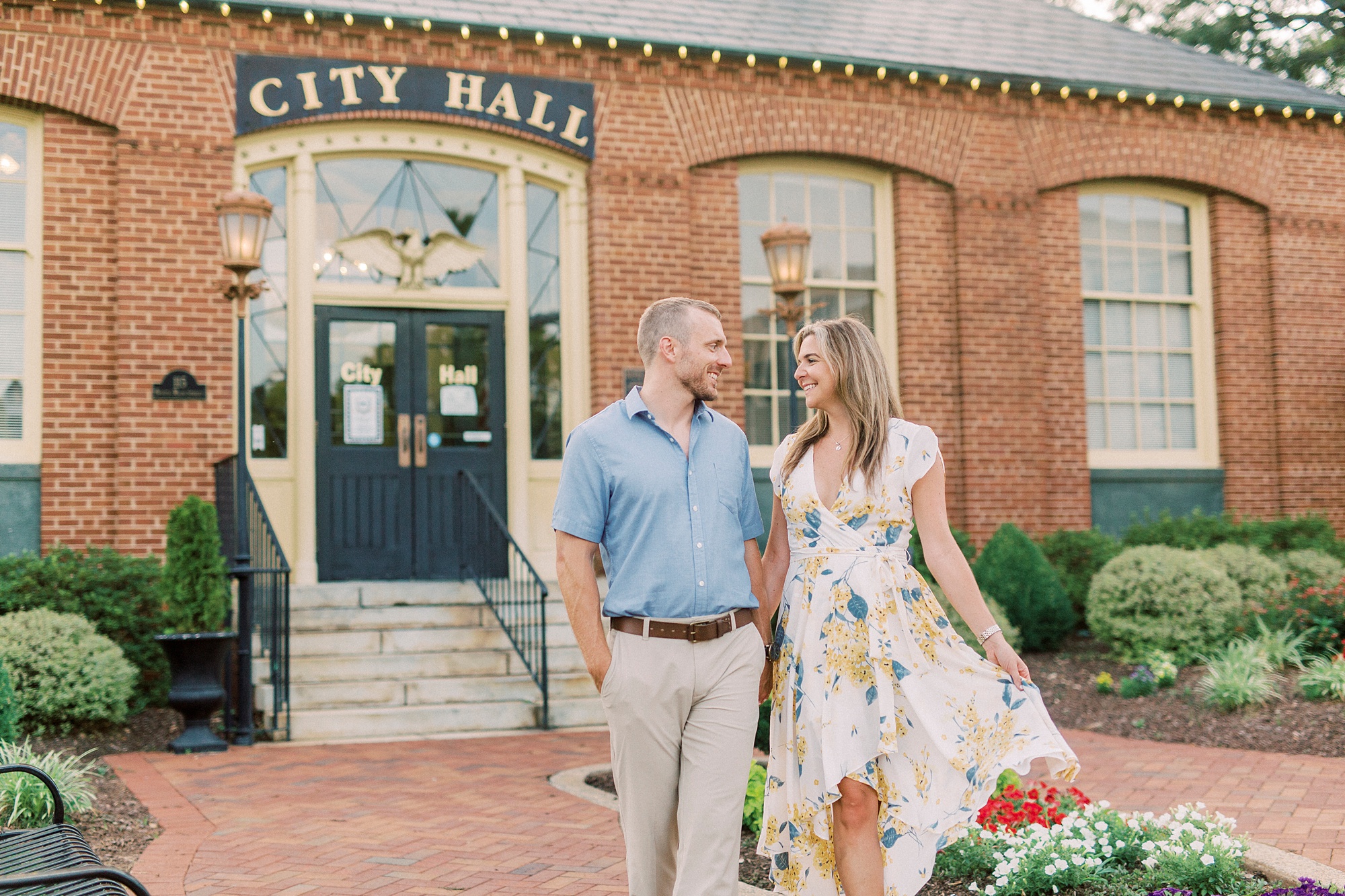 engaged couple walks in front of Downtown Belmont City Hall