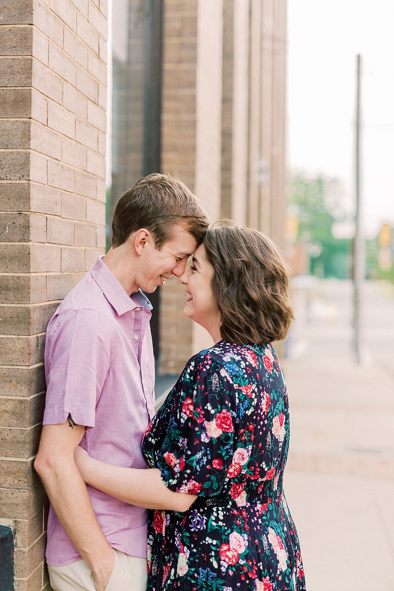 married couple leans against brick wall