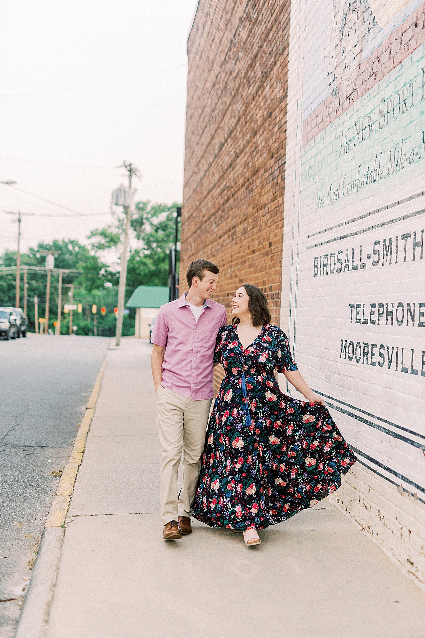 married couple poses near white mural in Downtown Mooresville