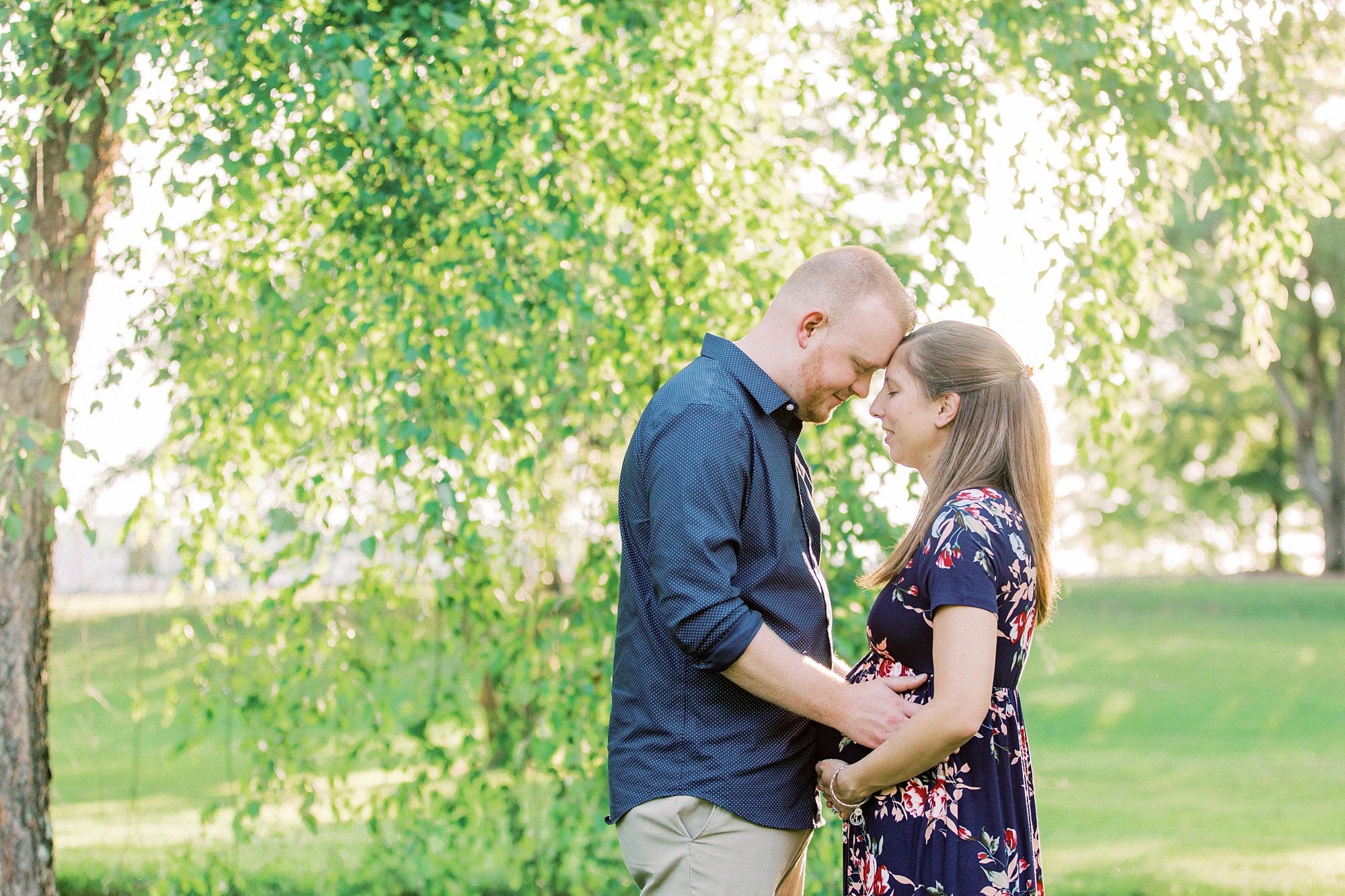 husband leans down to touch noses with wife during maternity photos in Rankin Lake Park