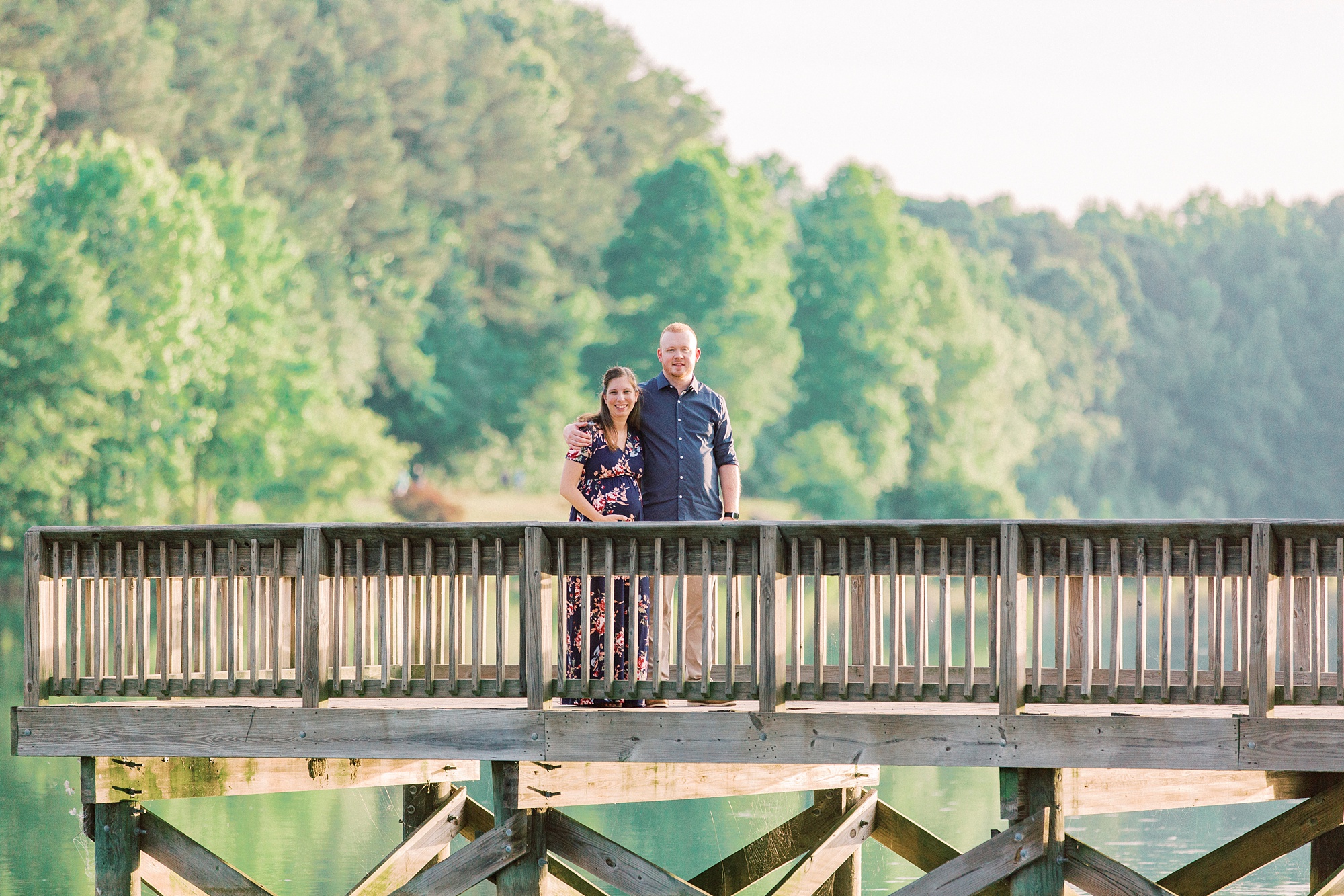 couple poses on wooden pier over water