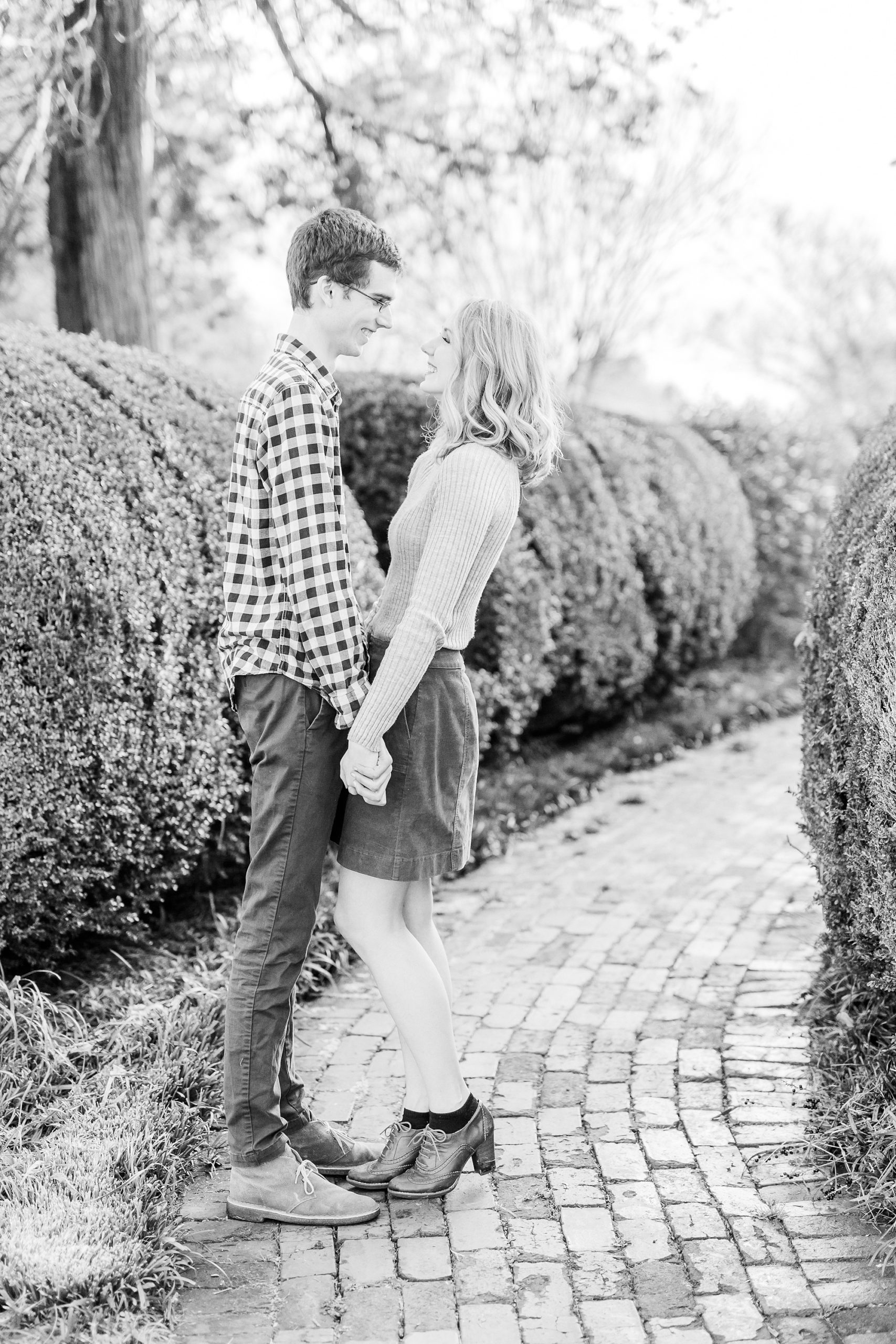 engaged couple holds hands standing on brick path at 1812 Hitching Post