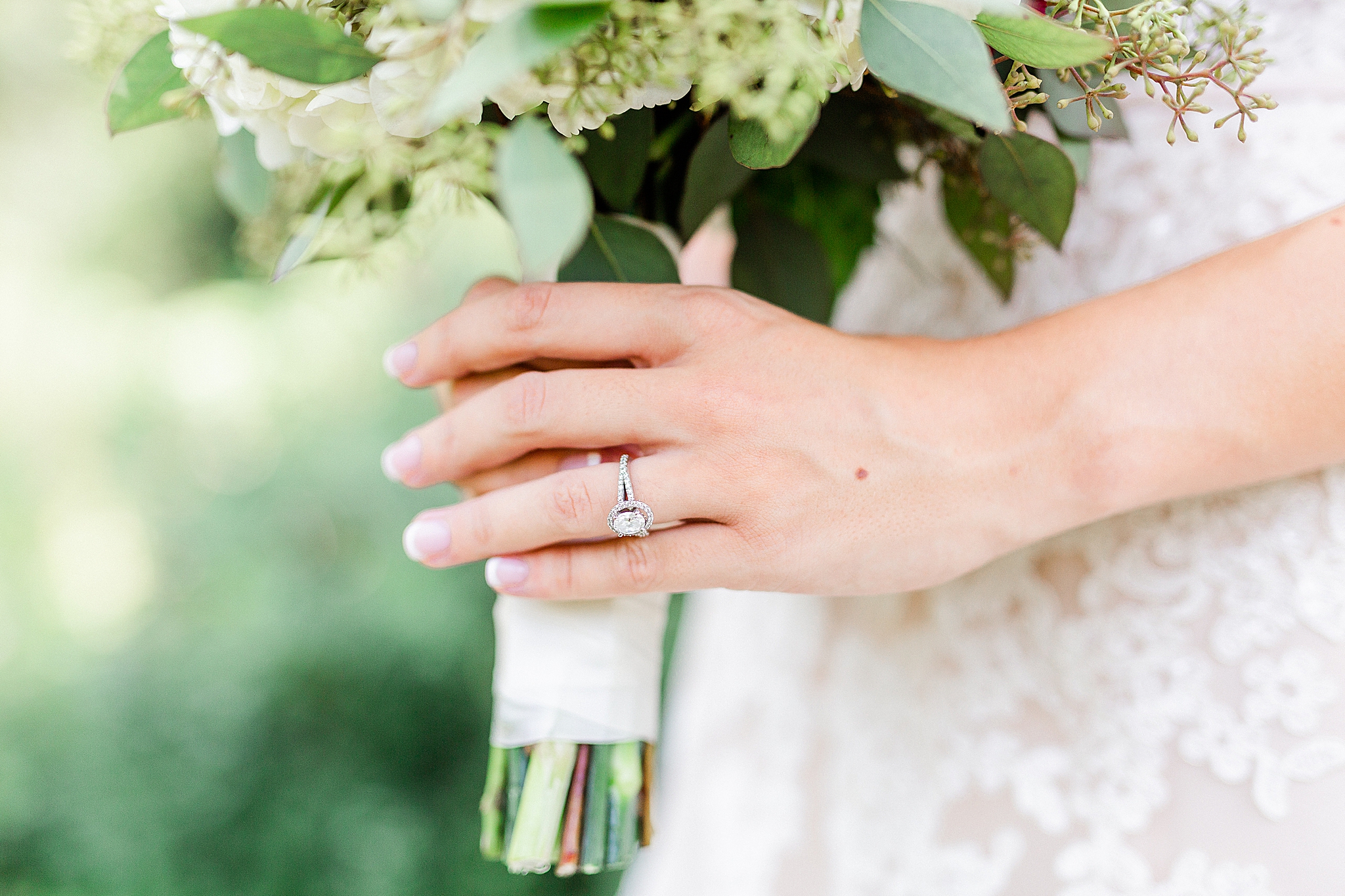 bride shows engagement ring on wedding bouquet