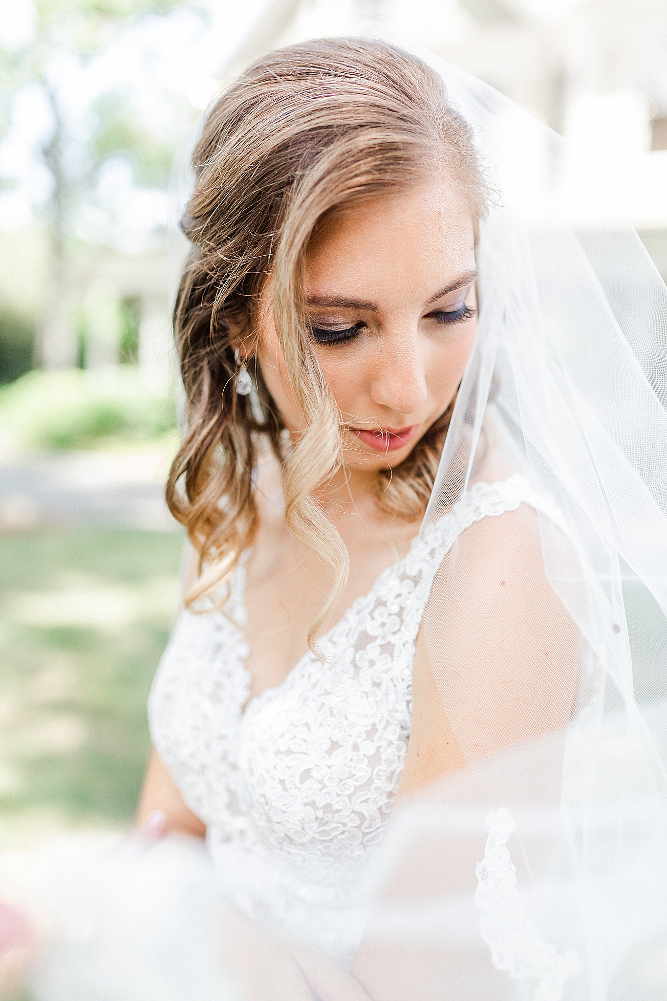 bride looks over shoulder with veil draped around her arms