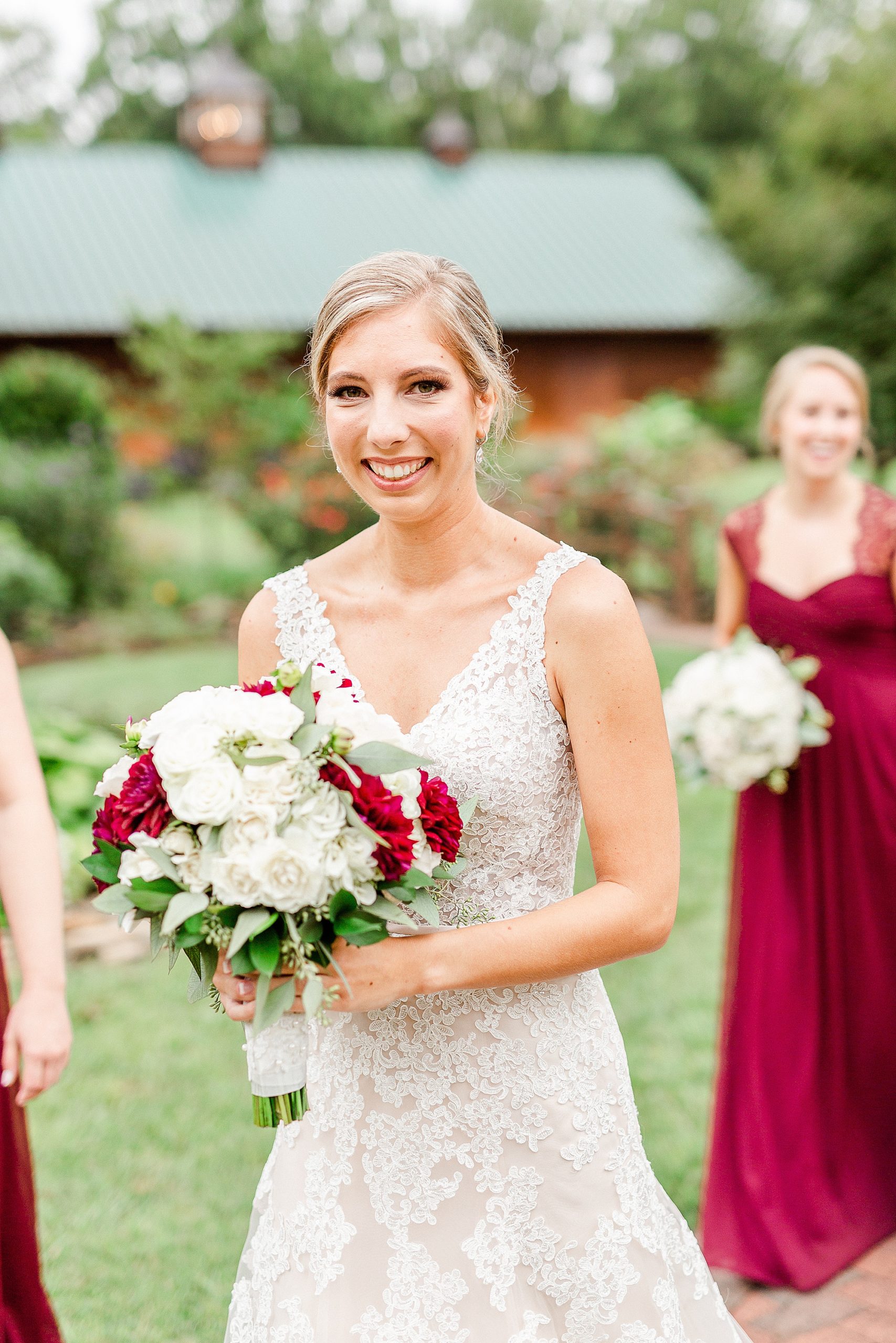 bride walks with bridesmaids in red gowns at Alexander Homestead