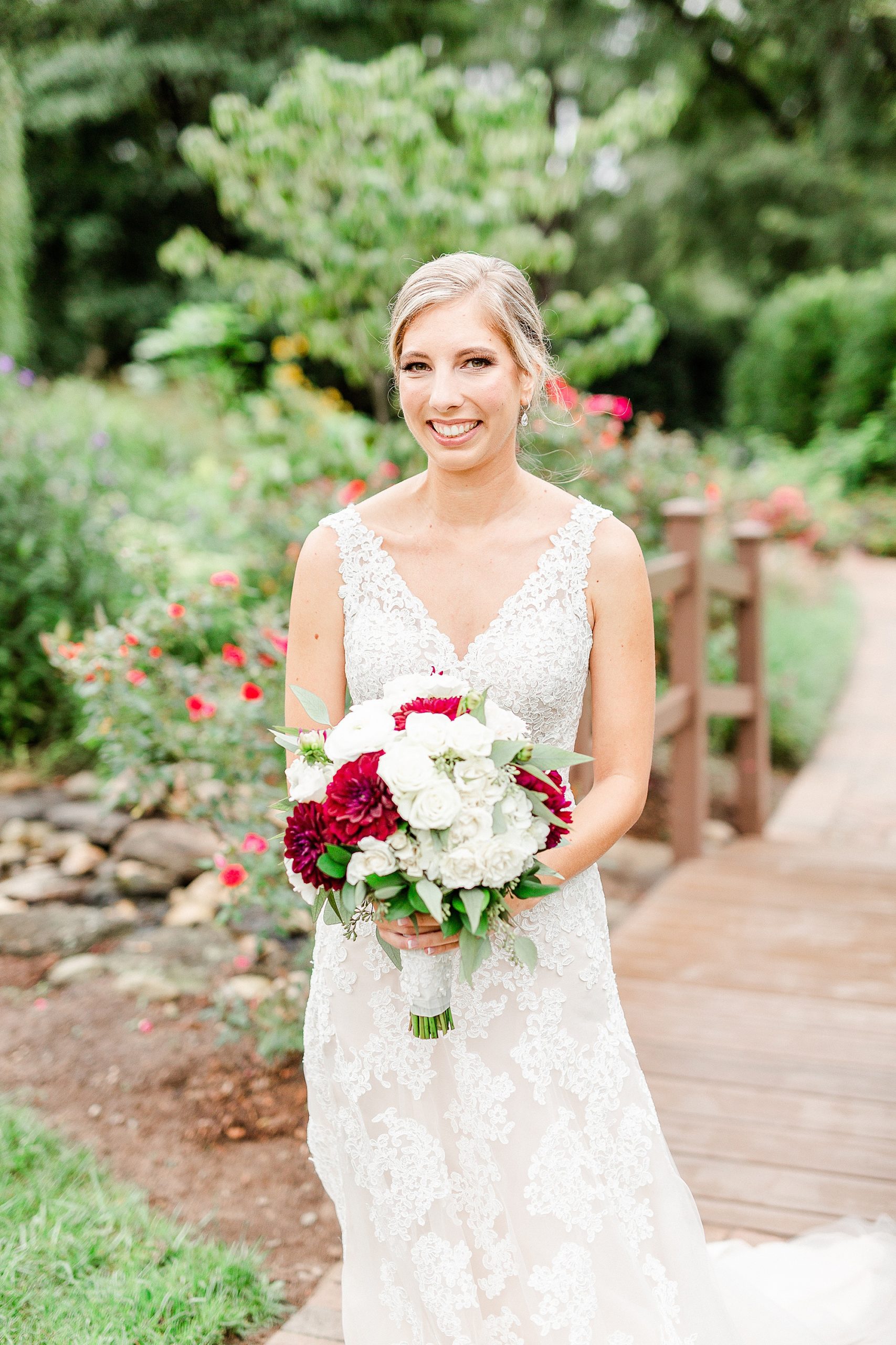 bride holds bouquet of white and red flowers at Alexander Homestead