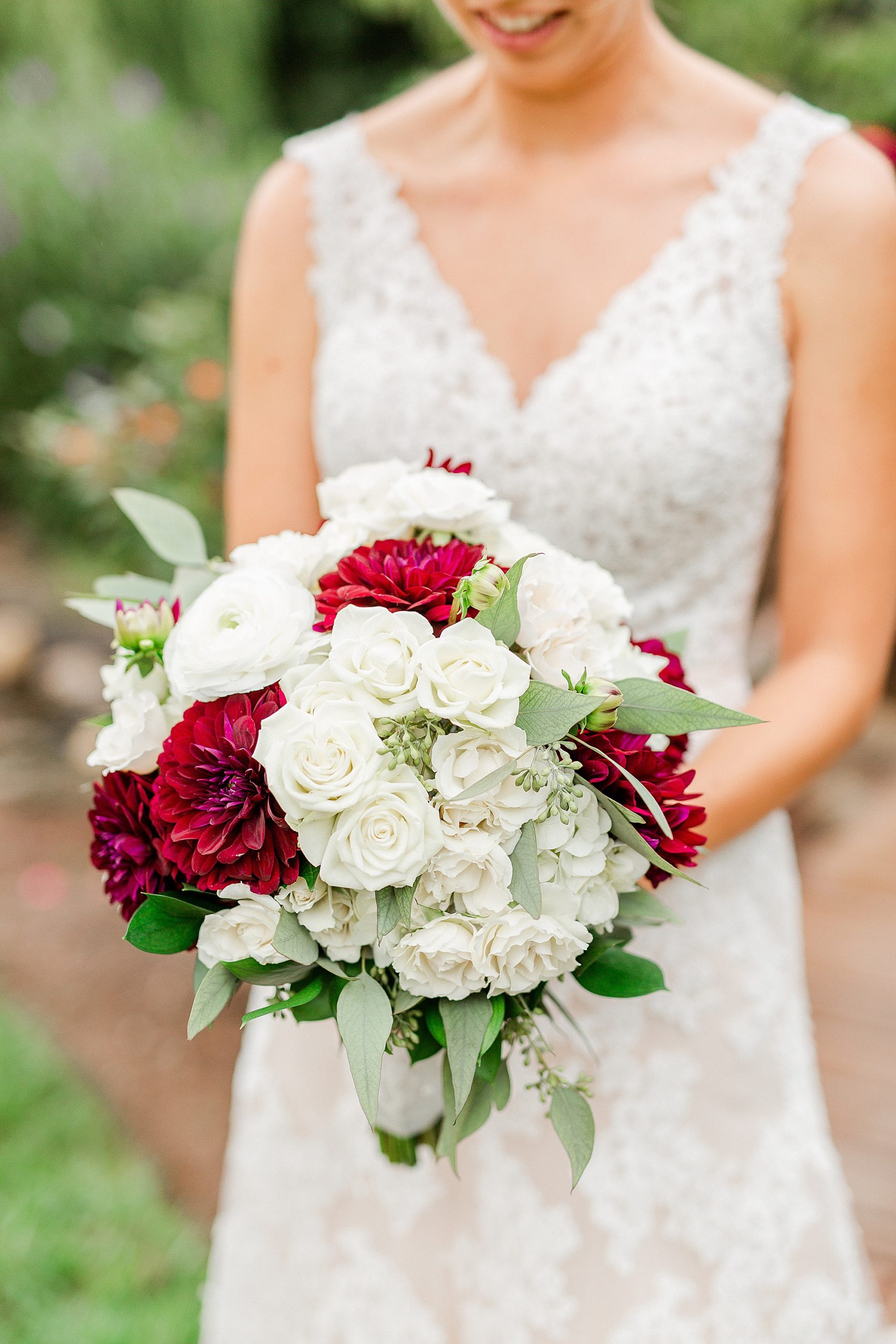 bride holds bouquet of white and red flowers