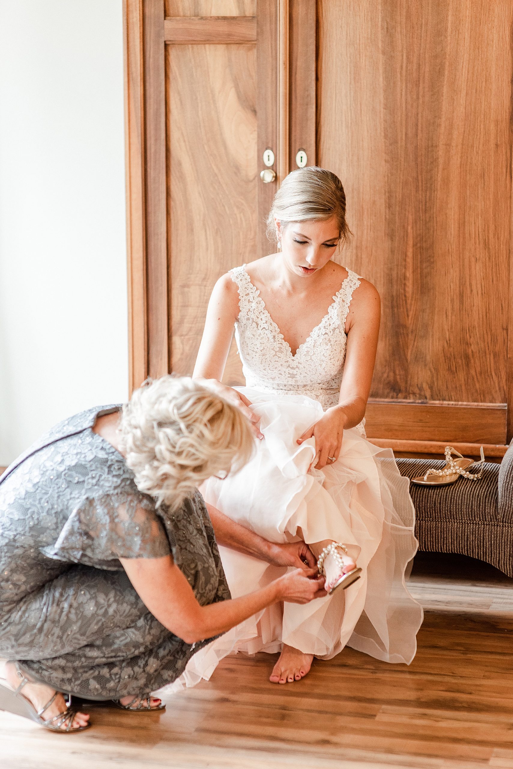 bride gets shoes on with mom