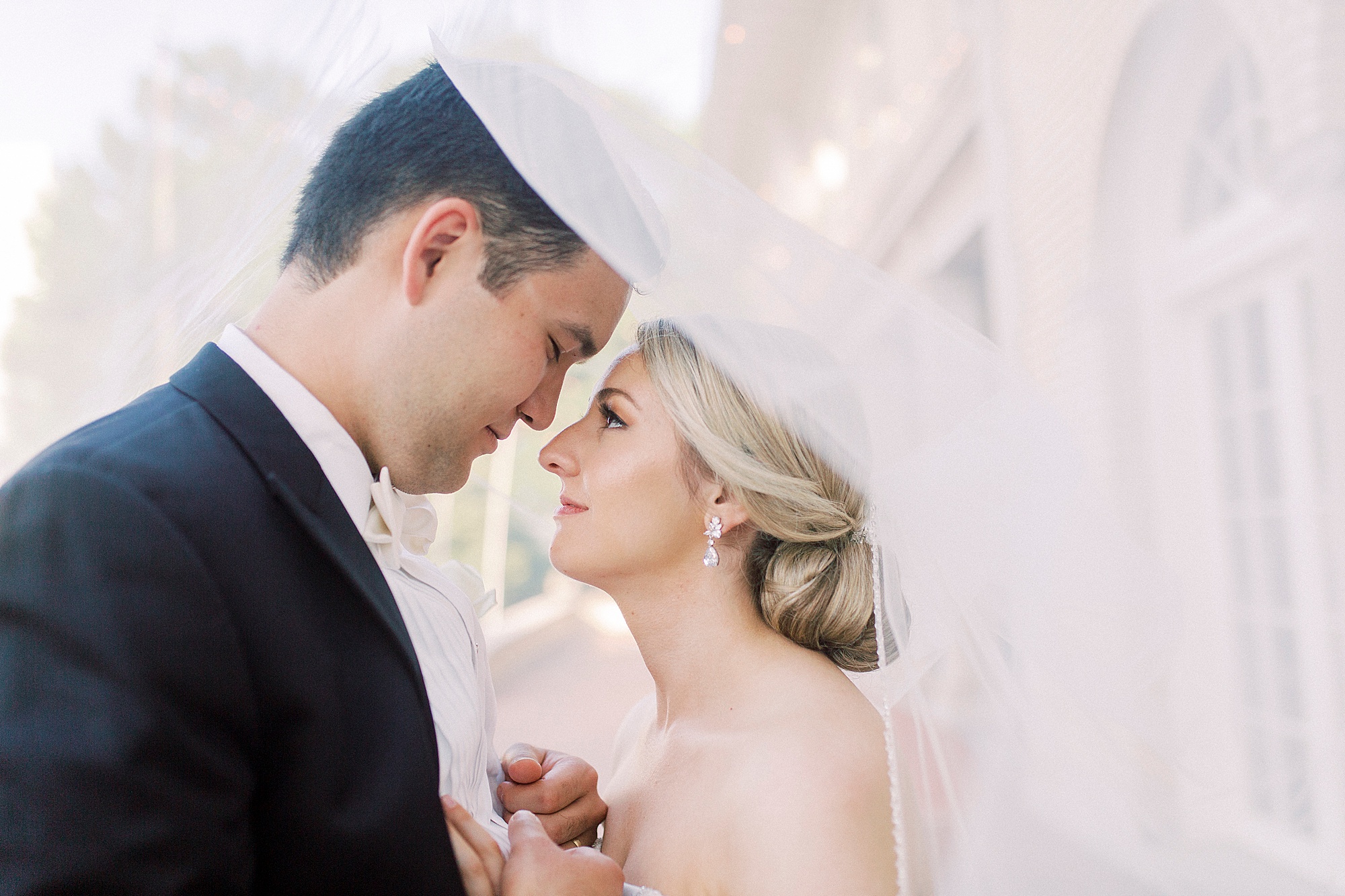 newlyweds pose under veil during wedding photos