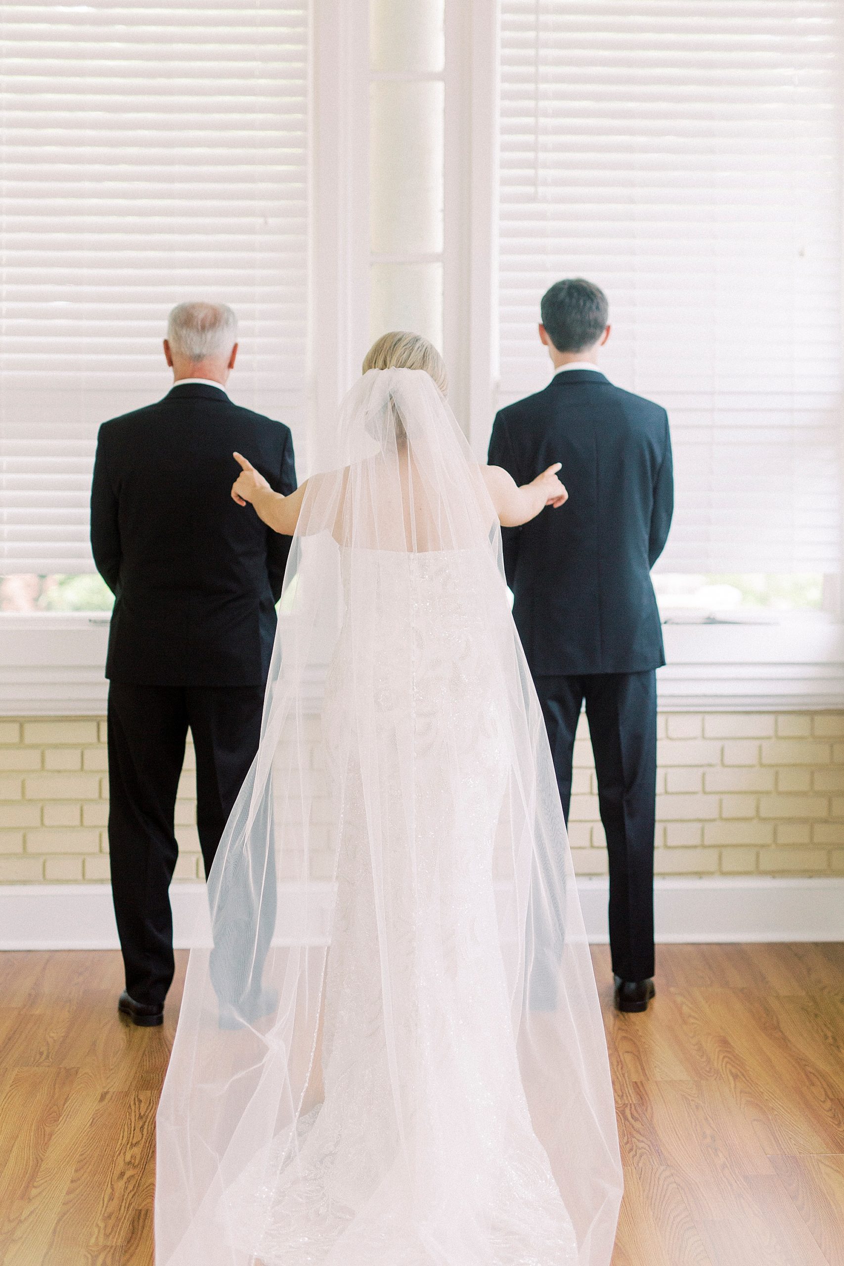 bride taps shoulders of groom and brother during first look