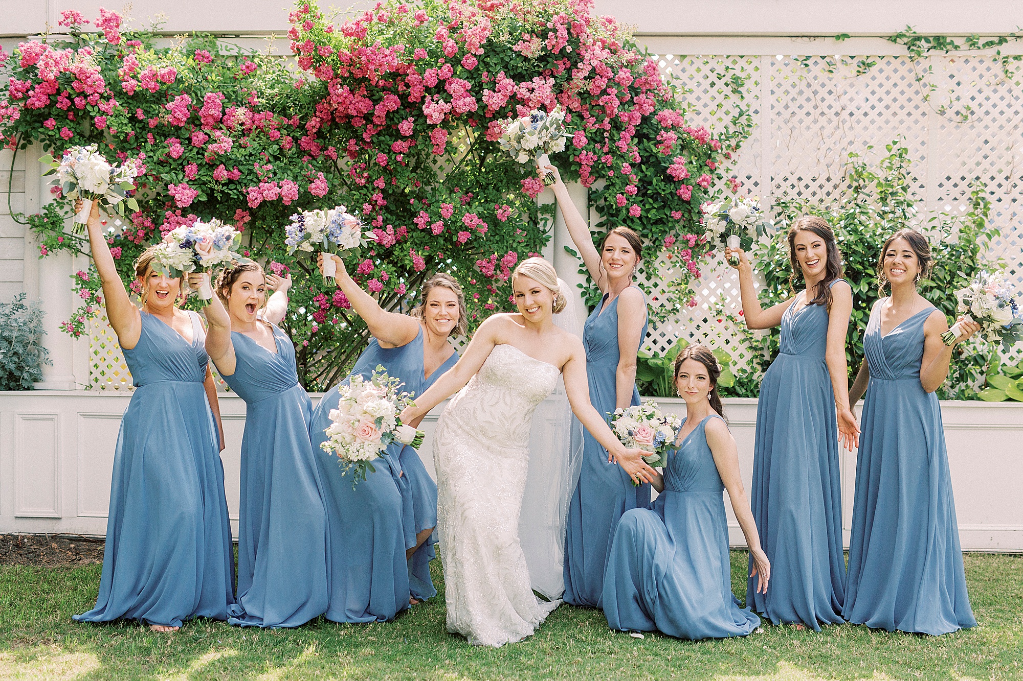 bridesmaids in blue gowns hold up bouquets