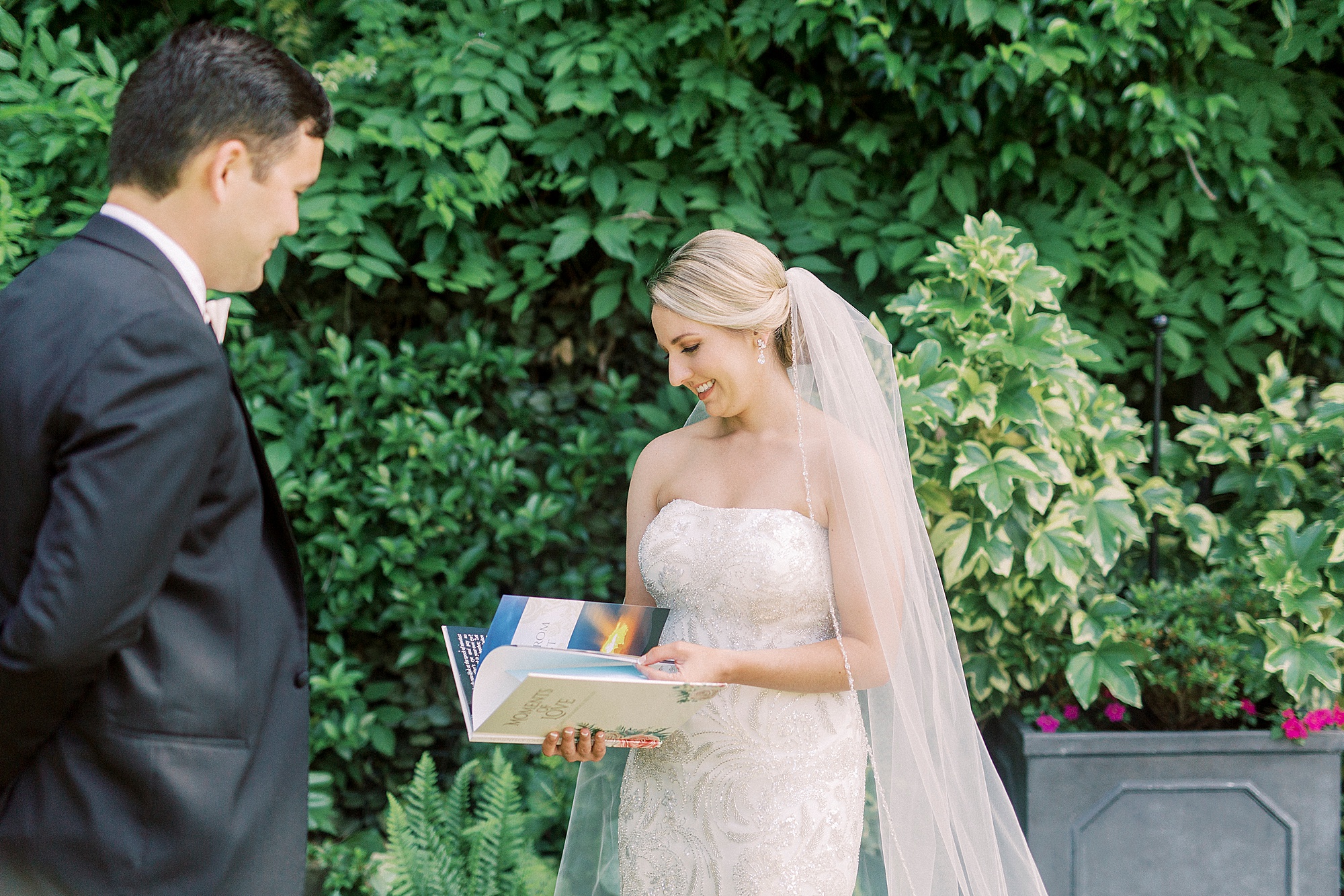 bride looks at book from groom during first look