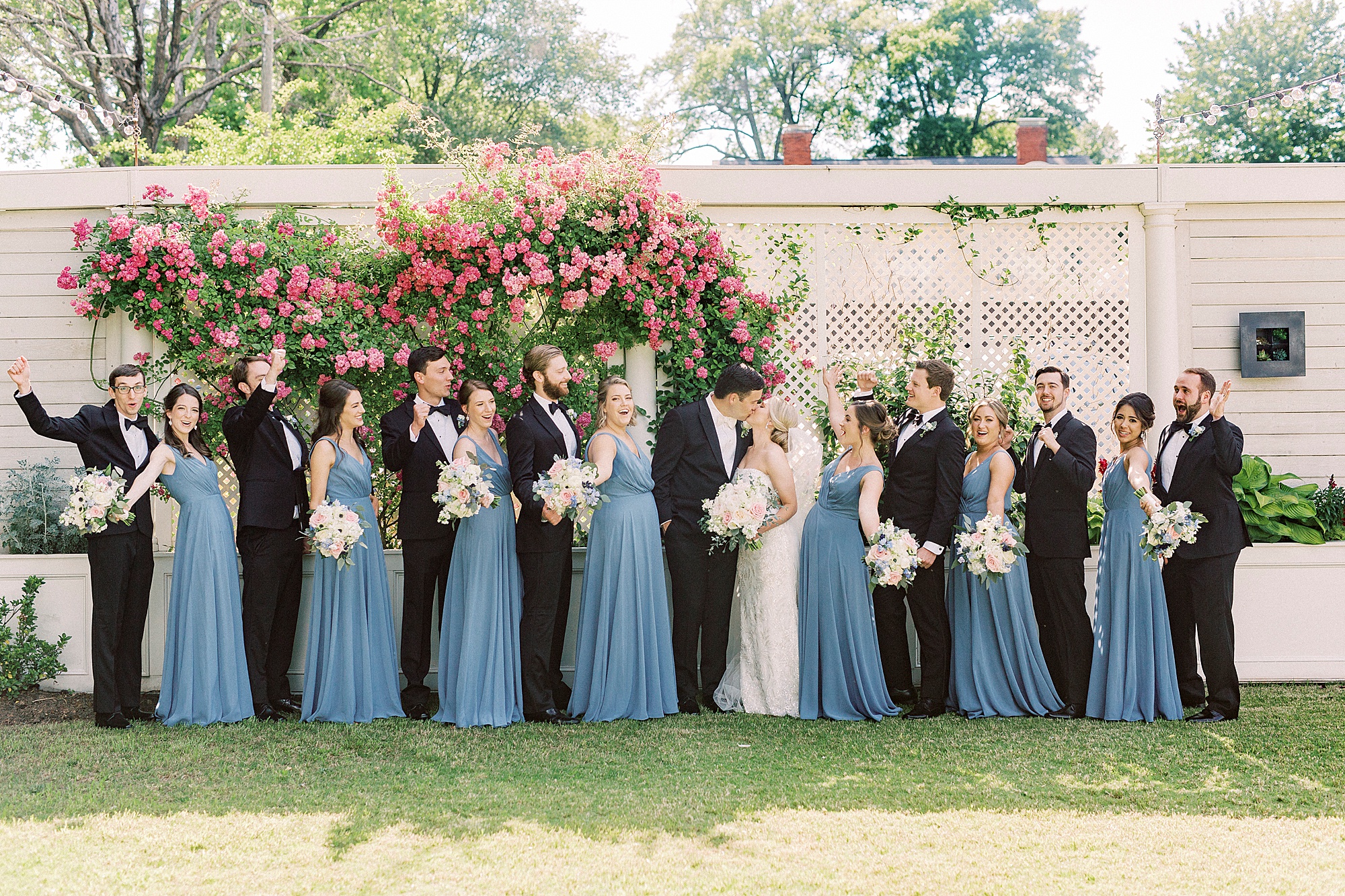 wedding party cheers while newlyweds kiss