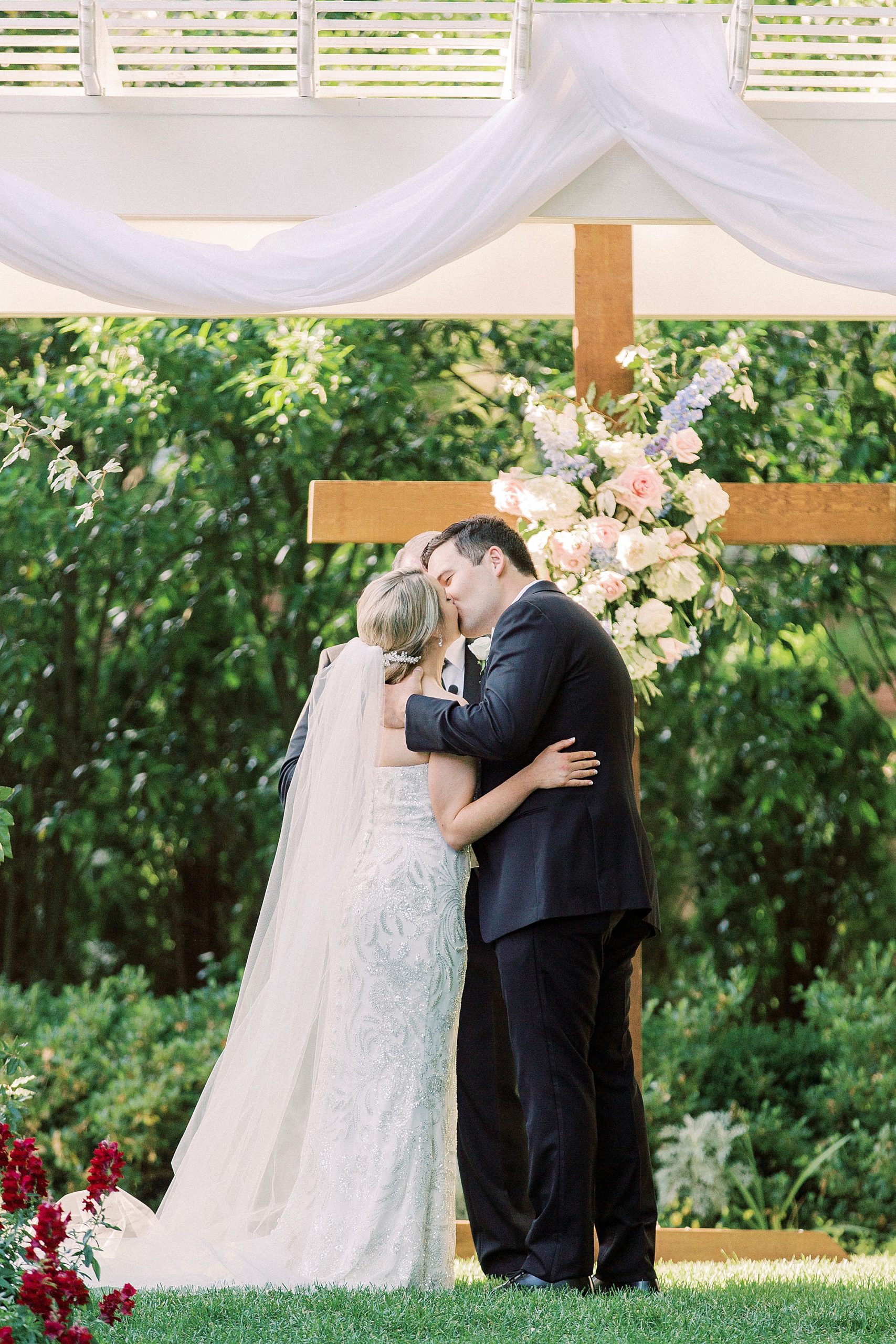 bride and groom kiss by wooden cross for outdoor wedding ceremony at Separk Mansion