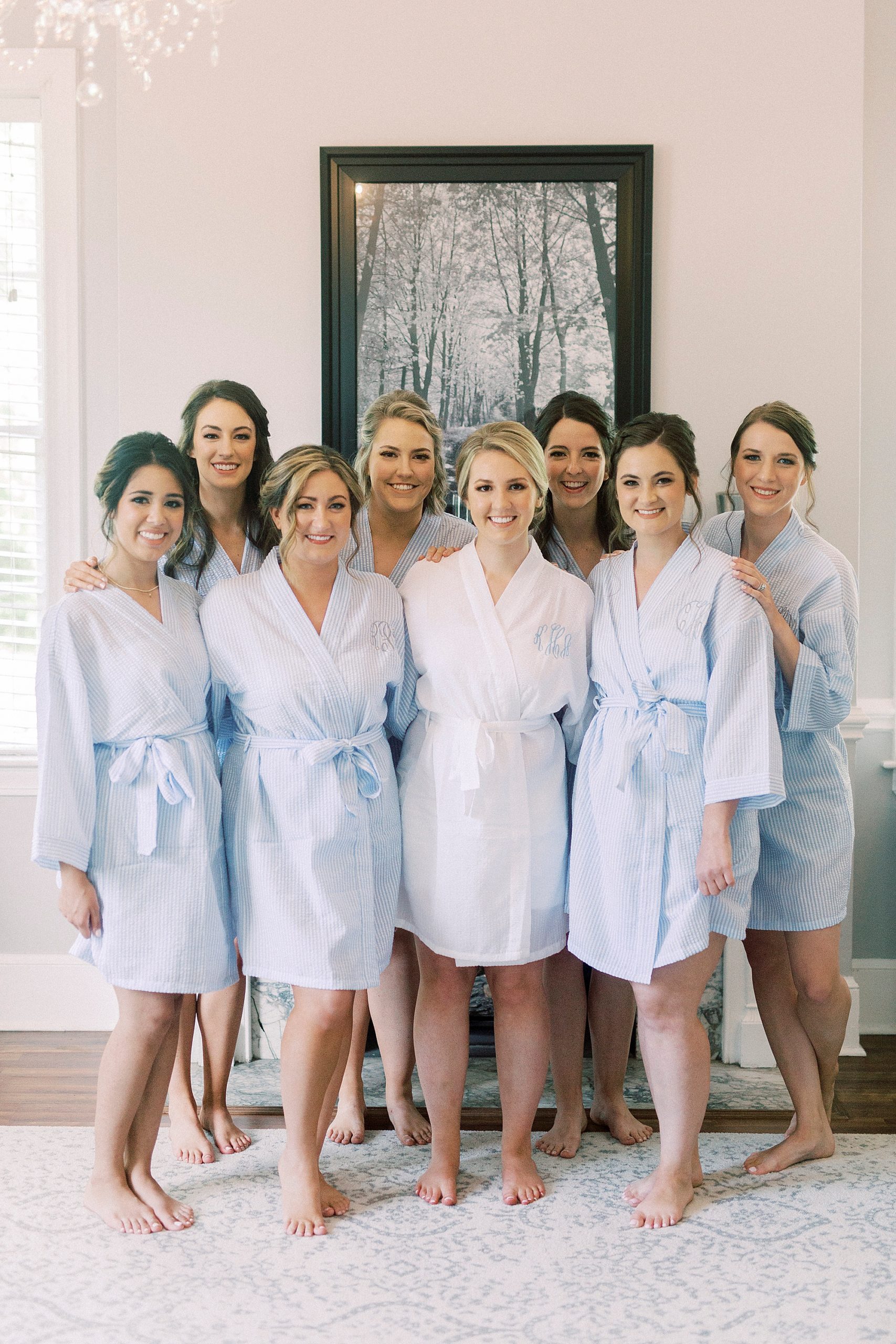 bride poses with bridesmaids in light blue robes