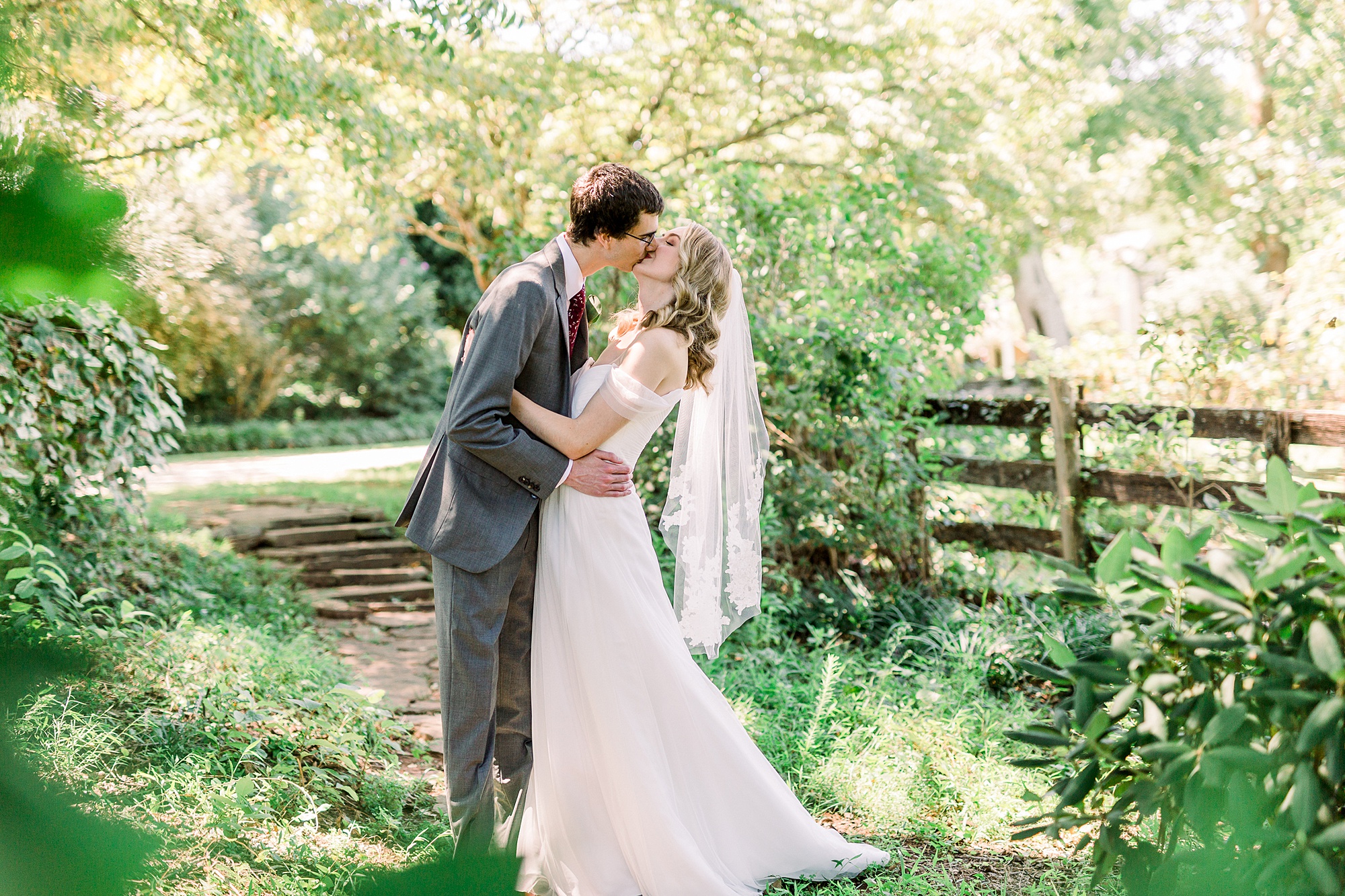 bride and groom kiss in gardens at 1812 Hitching Post