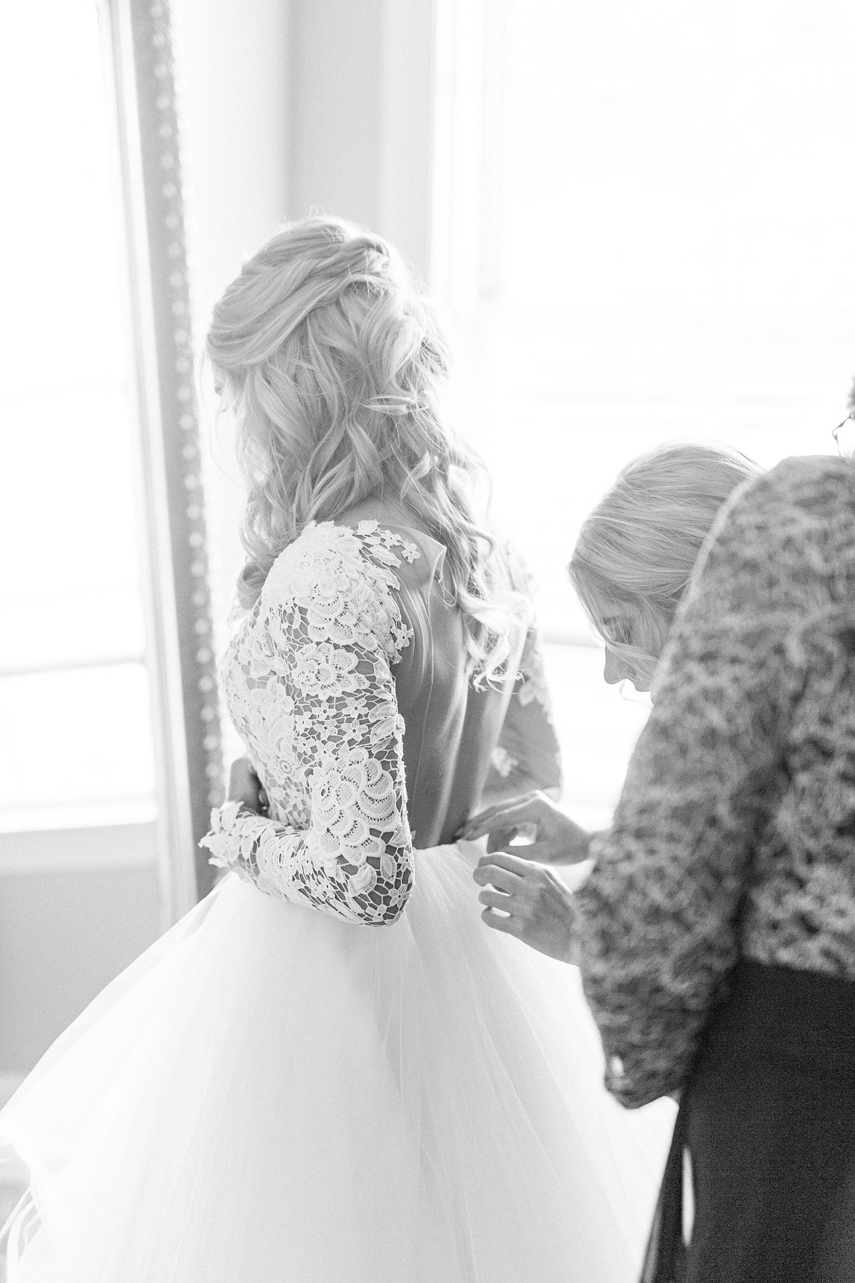 bridesmaid helps button up Hayden Olivia bridal gown
