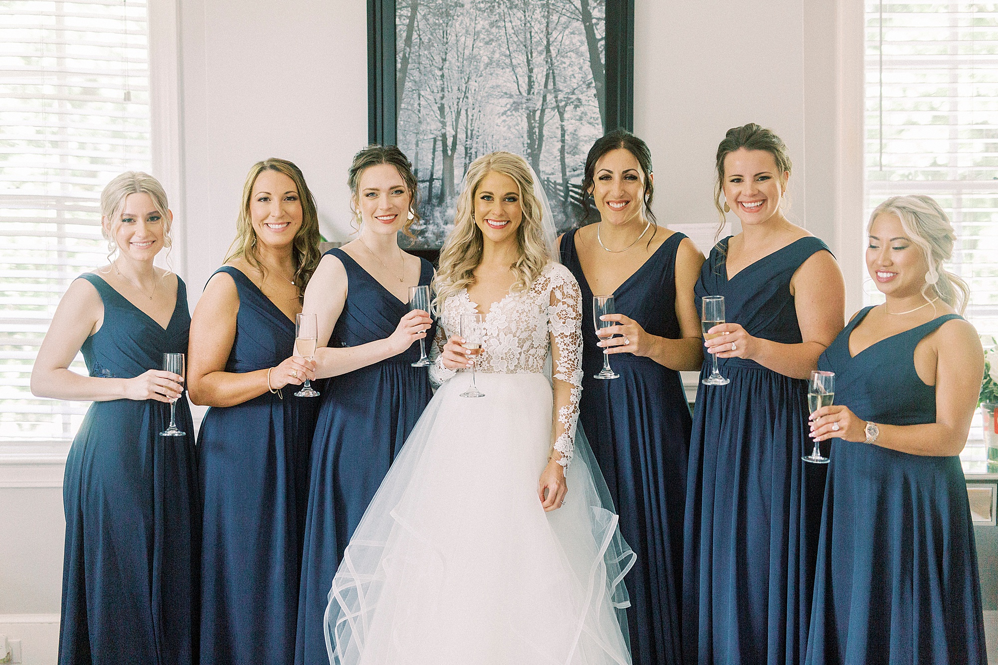 bride in hayden olivia bridal gown poses with bridesmaids in navy gown