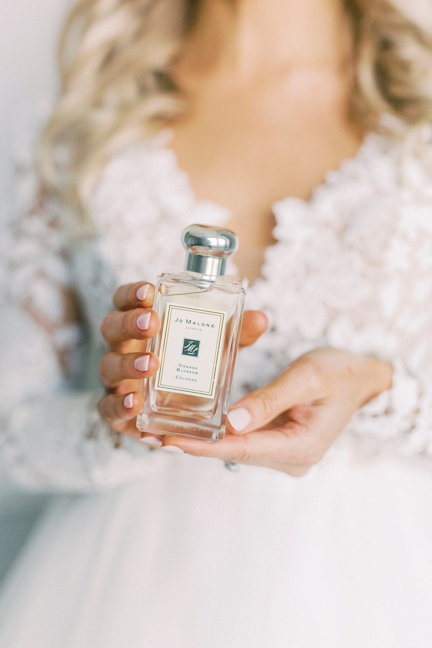 bride holds bottle of perfume wearing hayden olivia bridal gown