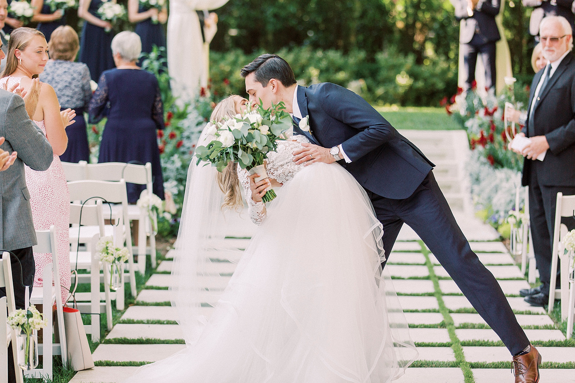 groom kisses bride at end of aisle during garden wedding ceremony at Separk Mansion