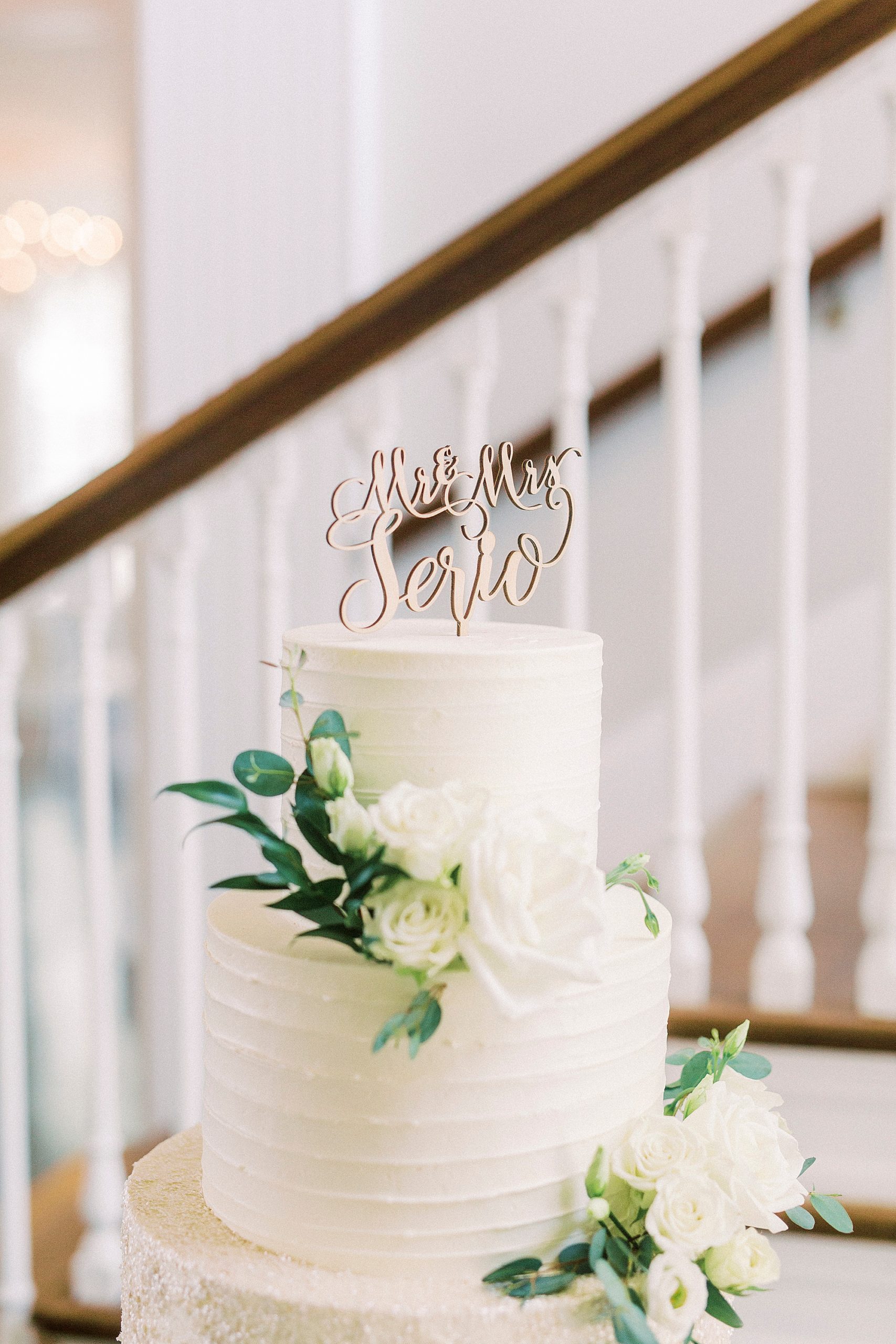 tiered wedding cake with wooden topper and floral accents