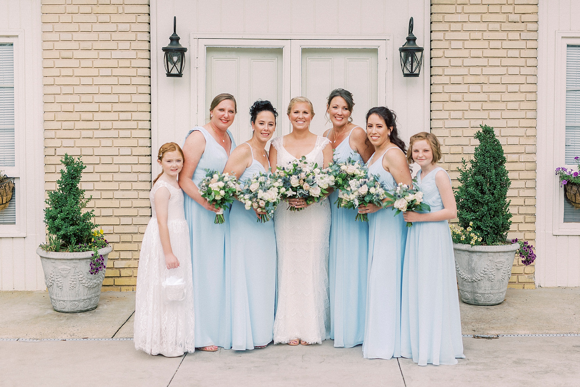 bride poses with bridesmaids in blue dresses